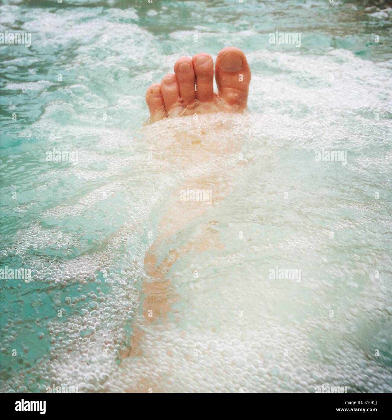 Einen Fuß in einen Pool. Stockfoto