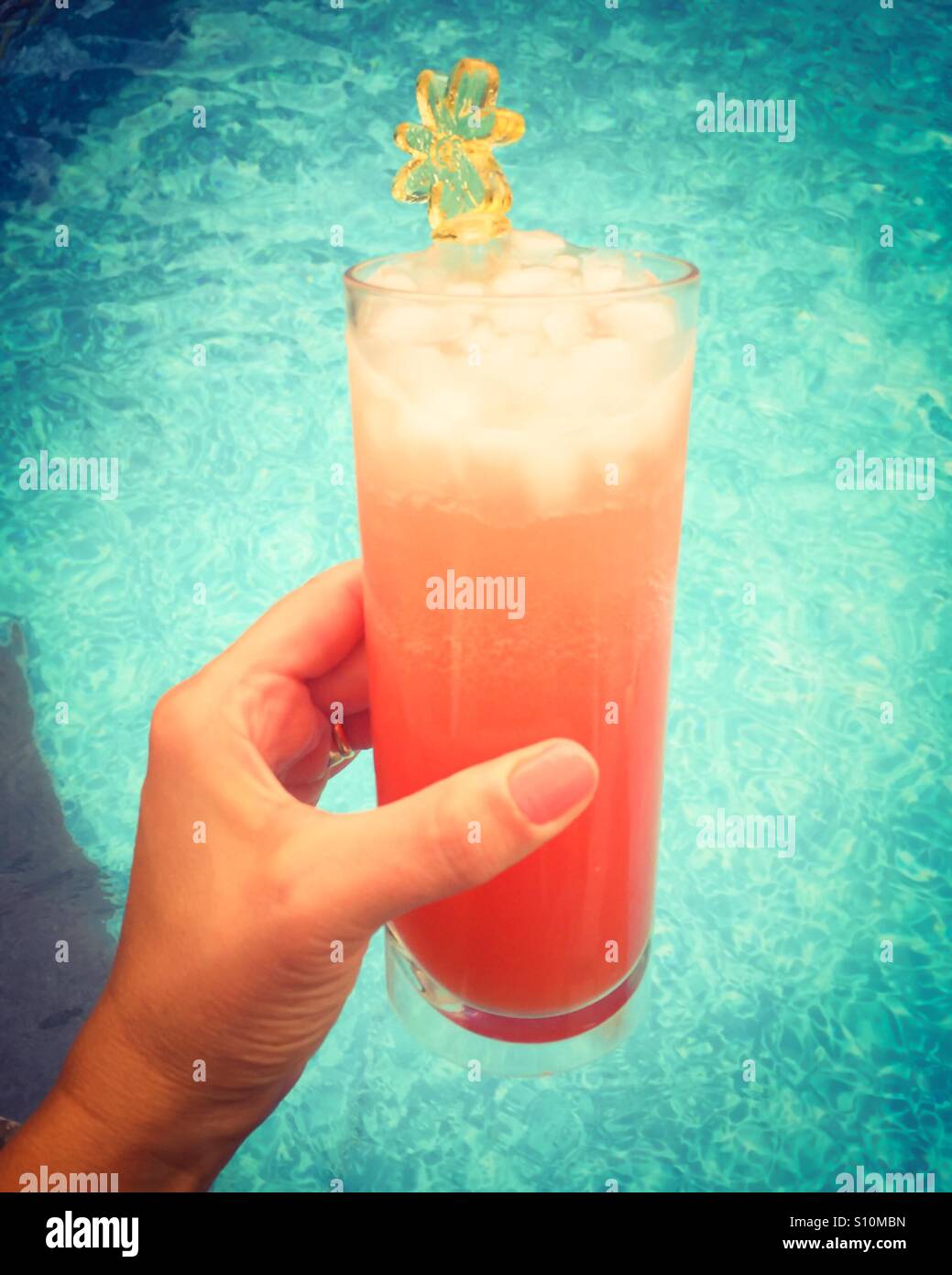Nahaufnahme der Hand einer Frau, die mit einem eiskalten Getränk an einem heißen Tag neben einem Schwimmbad. - Smartphone-aufgenommenes Stockfoto