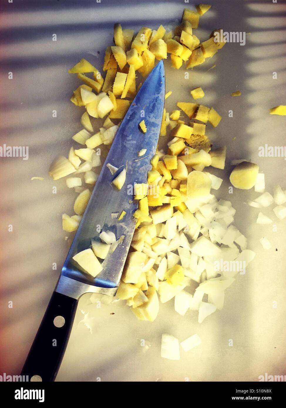 Messer und gehackten Knoblauch und Zwiebel auf ein Schneidebrett in Prep Küchenbereich - Smartphone-aufgenommenes Stockfoto
