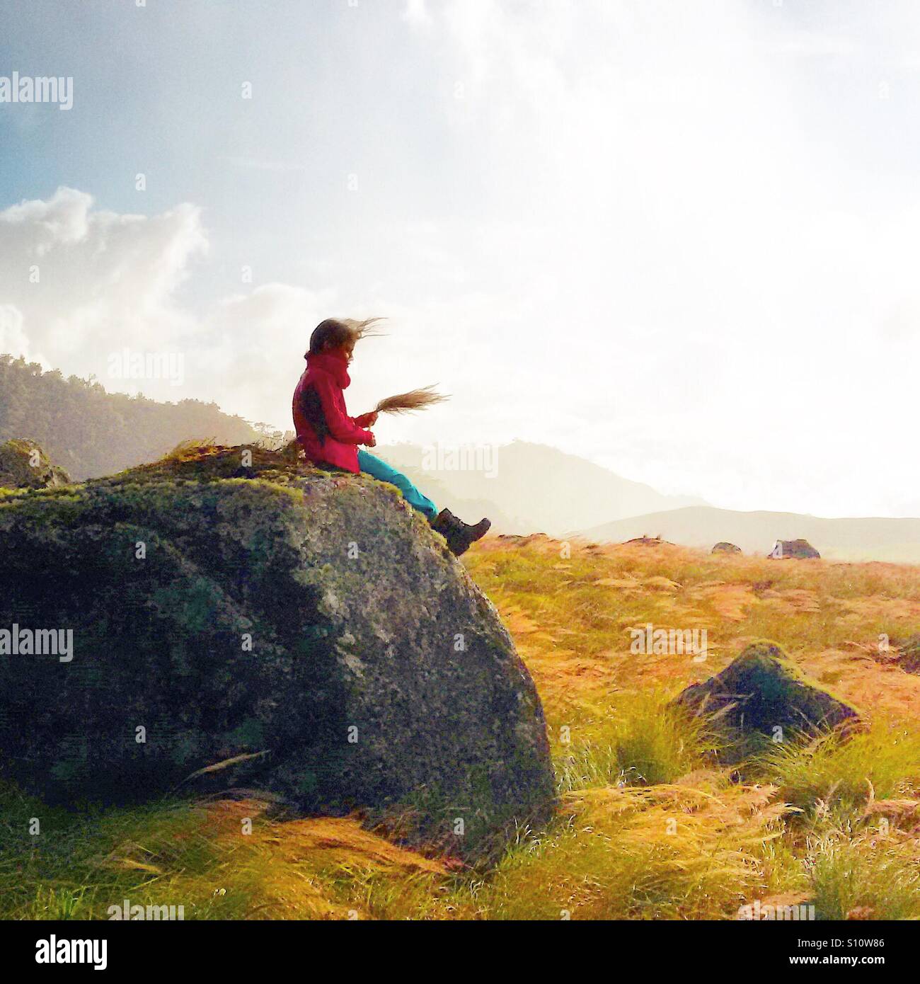 Kind sitzt auf dem Wind geblasen Rock in einem alten Lavastrom am Fuße des Volcan Baru in der Republik Panama. Stockfoto