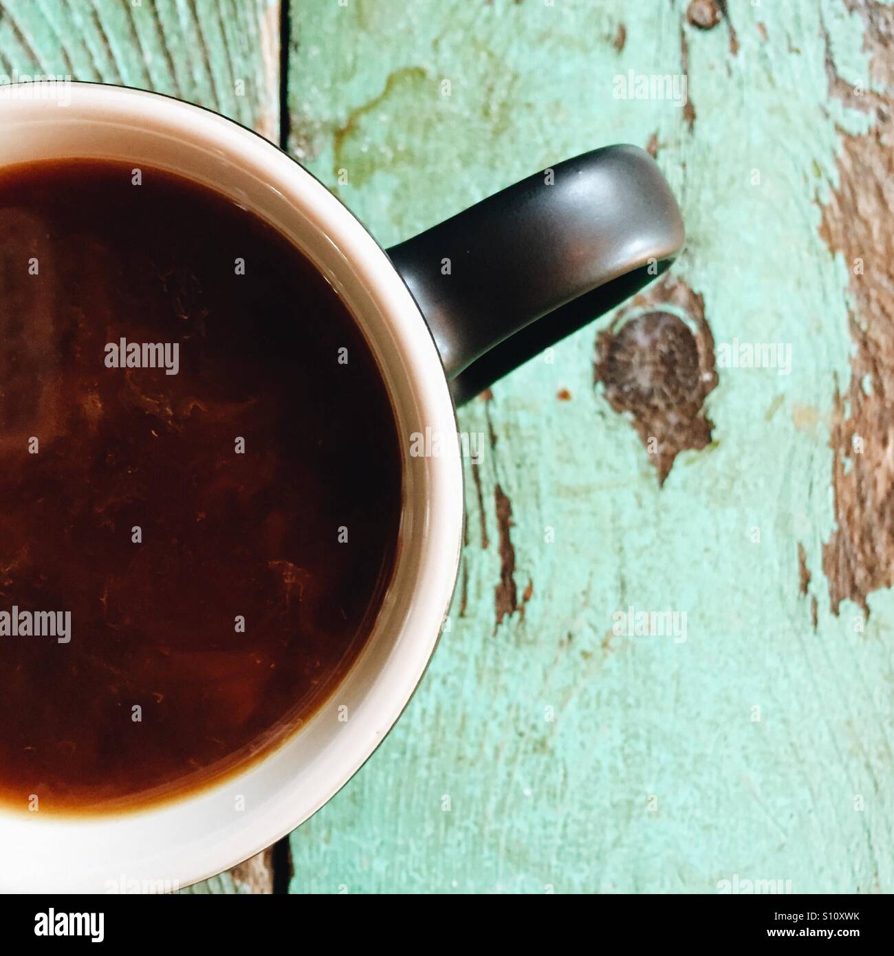 Ein overhead Nahaufnahme von einer frischen Tasse Kaffee mit ein bisschen Creme auf einem Holztisch. Stockfoto