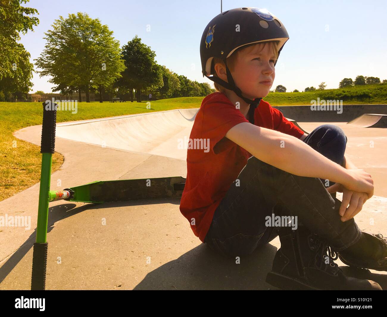 Ein 9-jähriger Junge sitzt mit seinem Roller Eaton Skatepark in Norwich Stockfoto