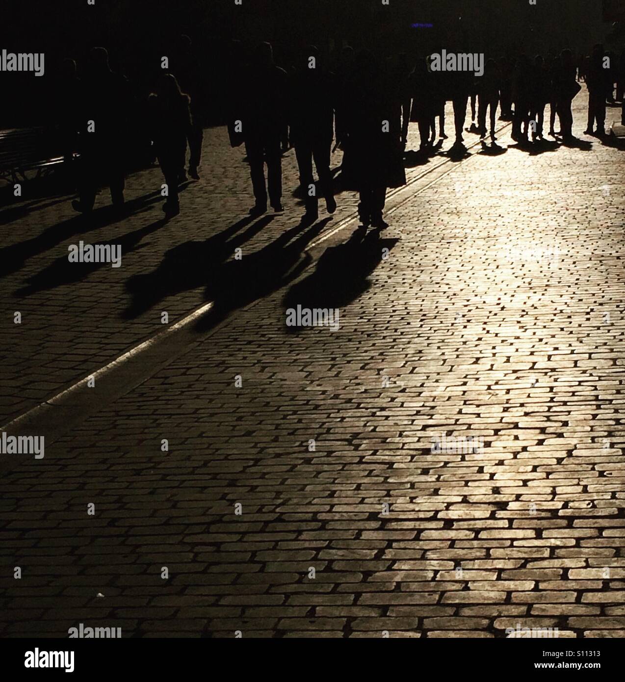 Silhouetten und Schatten von Menschen auf gepflasterte Fußgängerzone - Smartphone-aufgenommenes Stockfoto