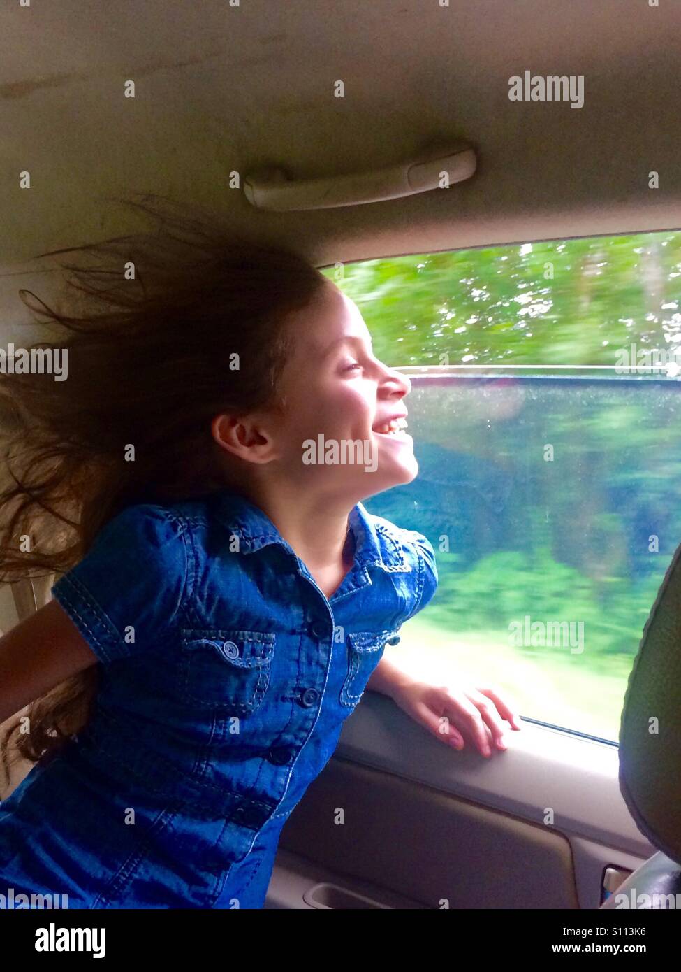 Junge temperamentvolle Mädchen lassen ihre Haare Schlag frei im Wind aus dem Autofenster. Stockfoto