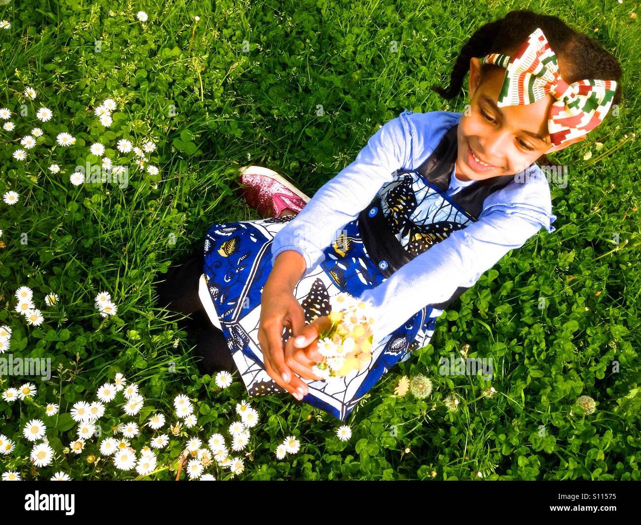 Junges Mädchen sitzen auf dem Rasen mit Blumen-Gänseblümchen. Stockfoto