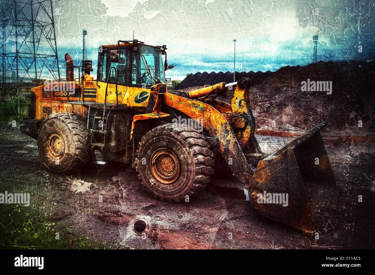 Ein Bagger oder Bulldozer in einer schmutzigen Industrieumgebung, in der Kohle geladen wird. - Smartphone-aufgenommenes Stockfoto