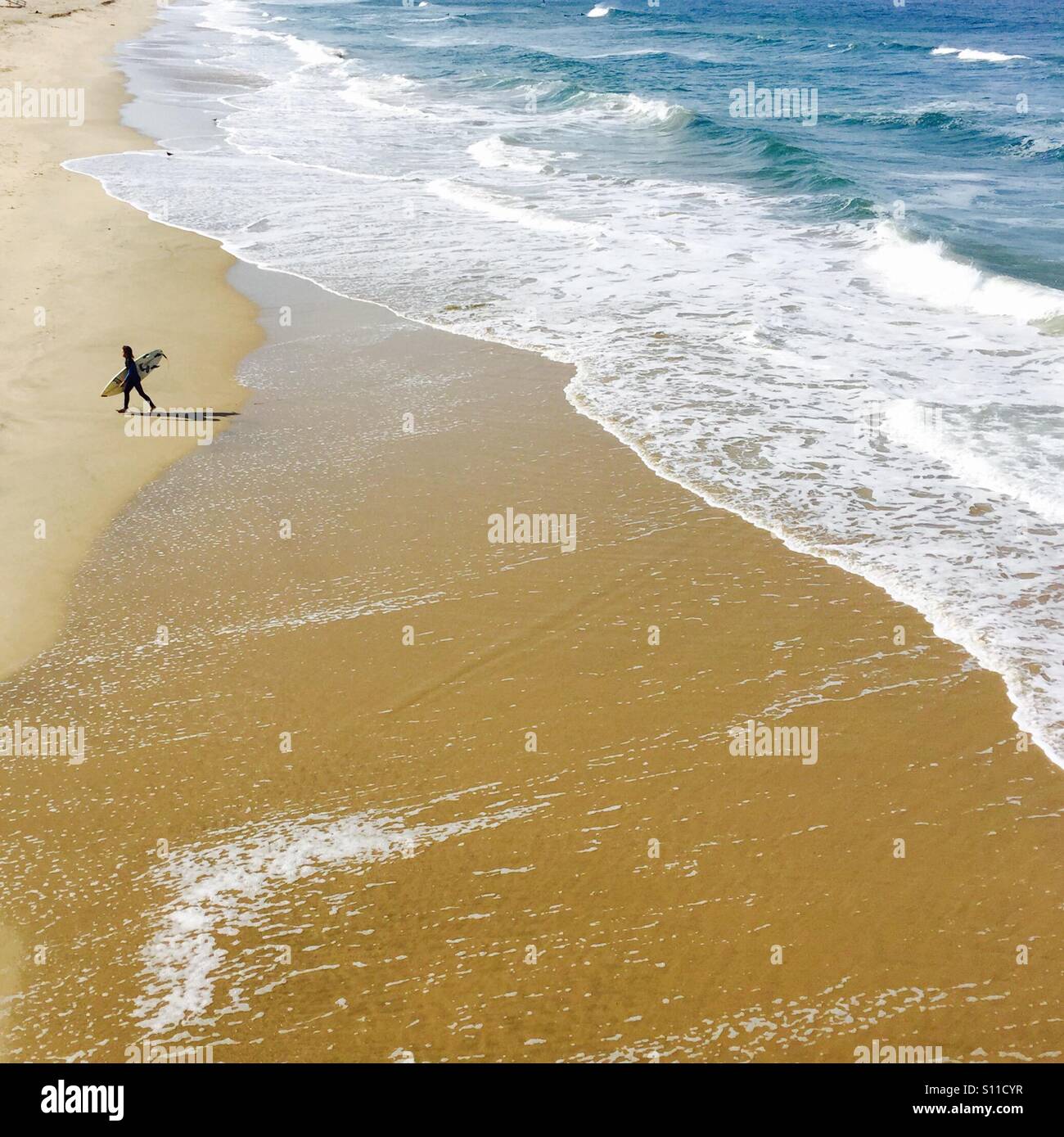 Eine einsame Surfer geht bis zum Strand.  Manhattan Beach, Kalifornien USA. Stockfoto
