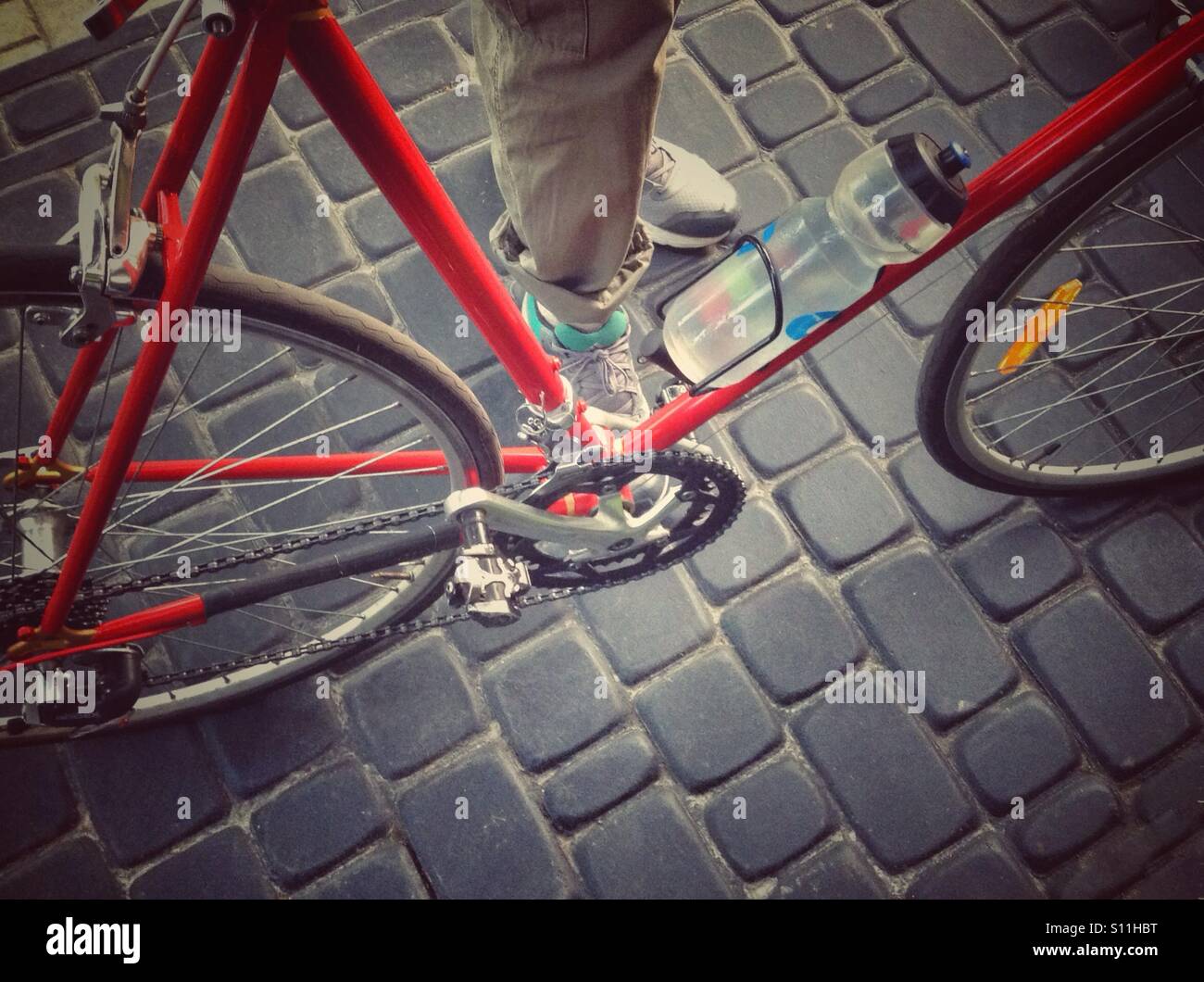 Fahrrad und Beine auf Pflasterstein Straße Stockfoto