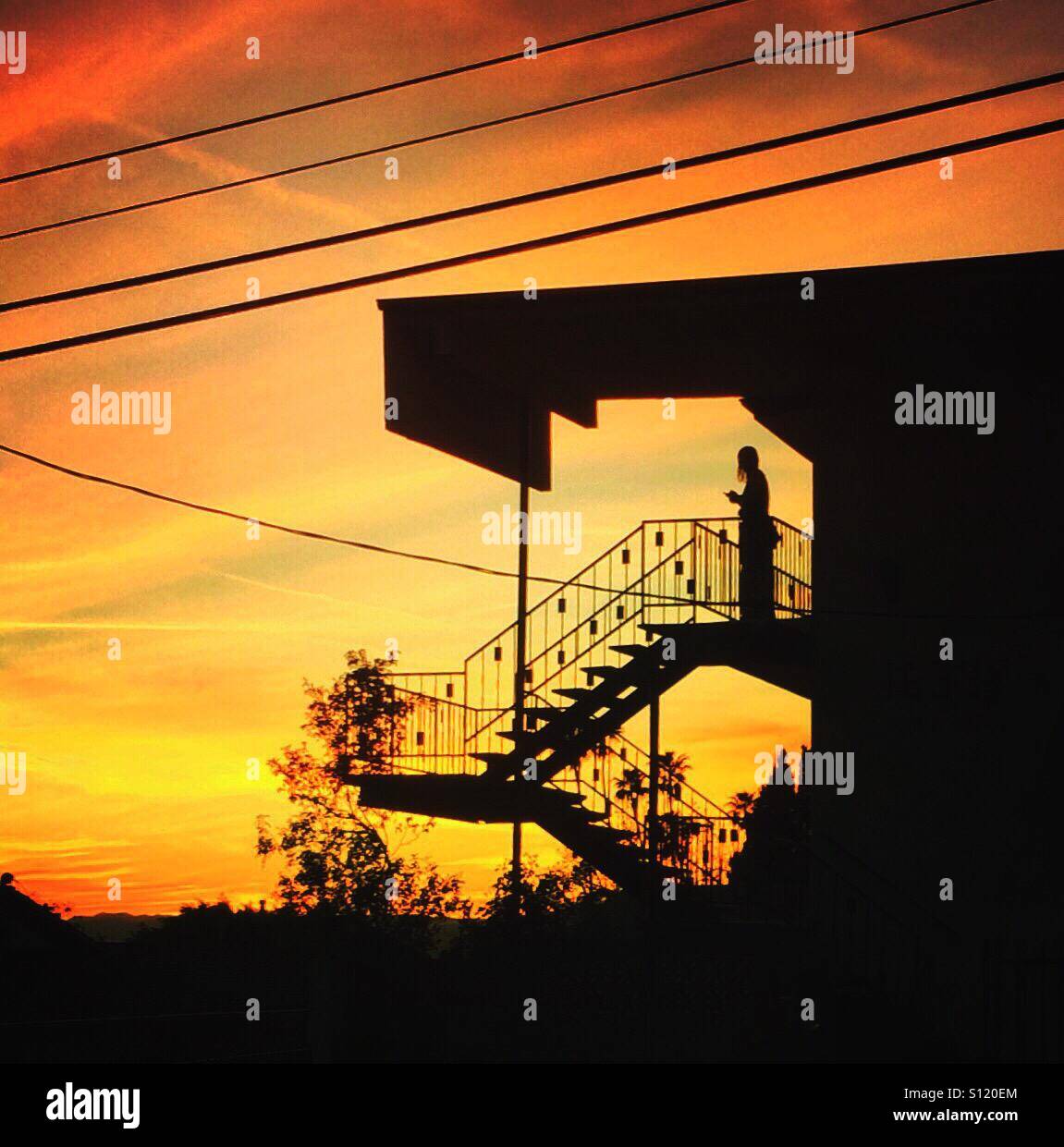 Person auf Treppe der Wohnanlage bei Sonnenuntergang Stockfoto