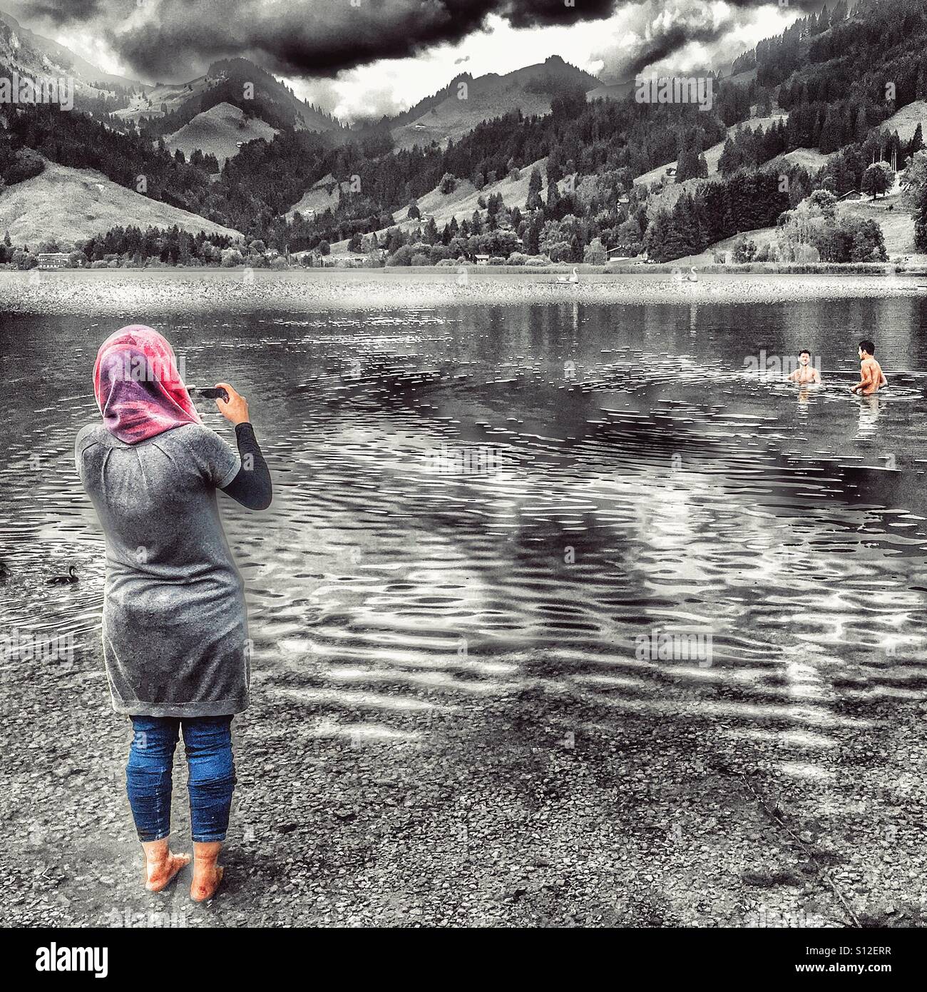Die muslimische Frau im Kopftuch nimmt Foto ihrer Brüder in einem See  schwimmen Stockfotografie - Alamy