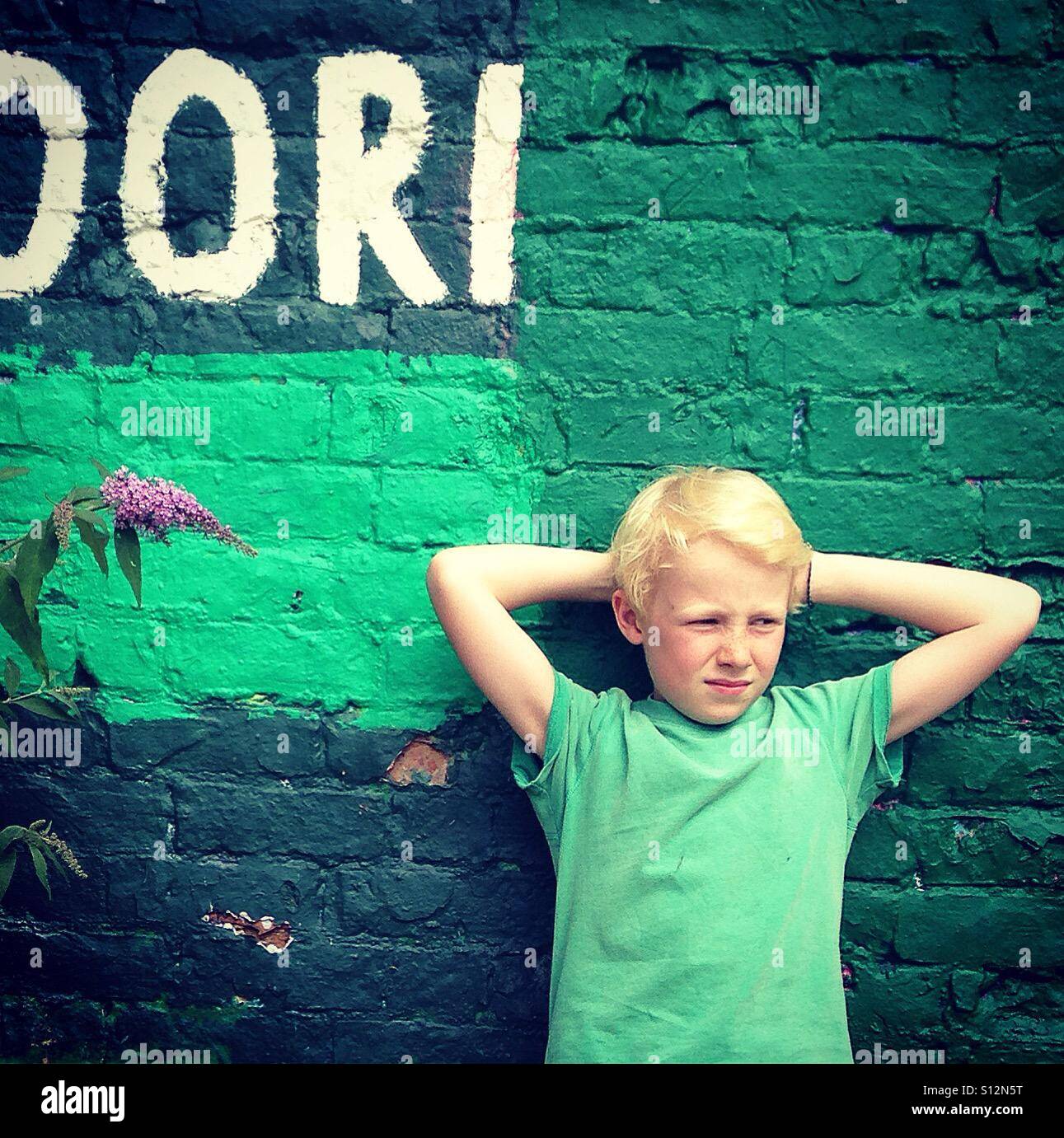 Young Boy eine grüne Mauer gelehnt Stockfoto
