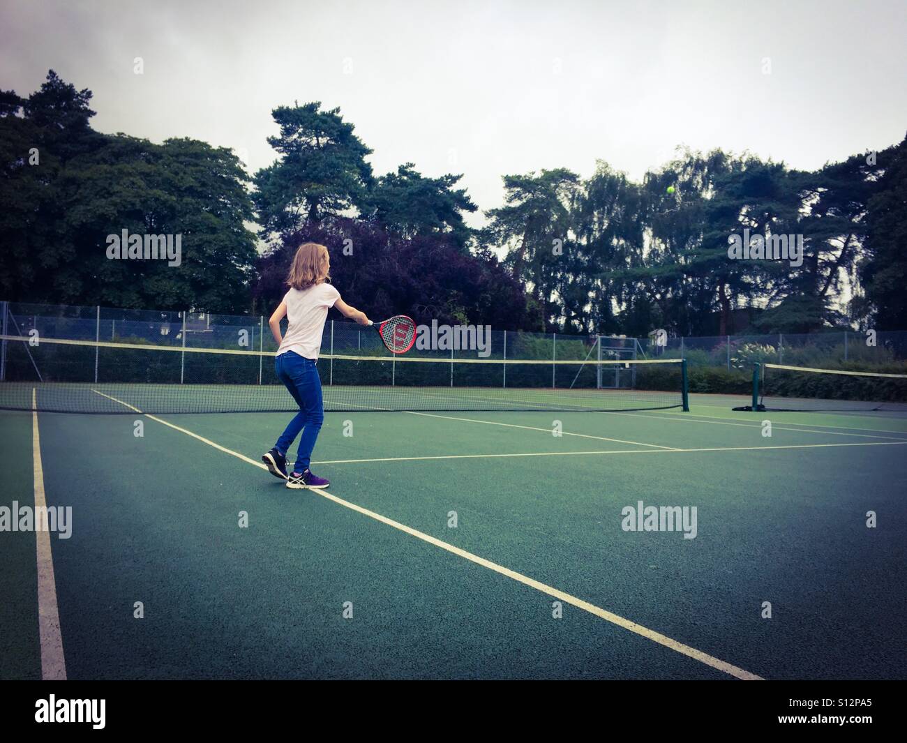 Ein 12 Jahre altes Mädchen üben ihre Tennis-Techniken auf einen leeren Platz im Waterloo Park in Norwich, Großbritannien. Stockfoto