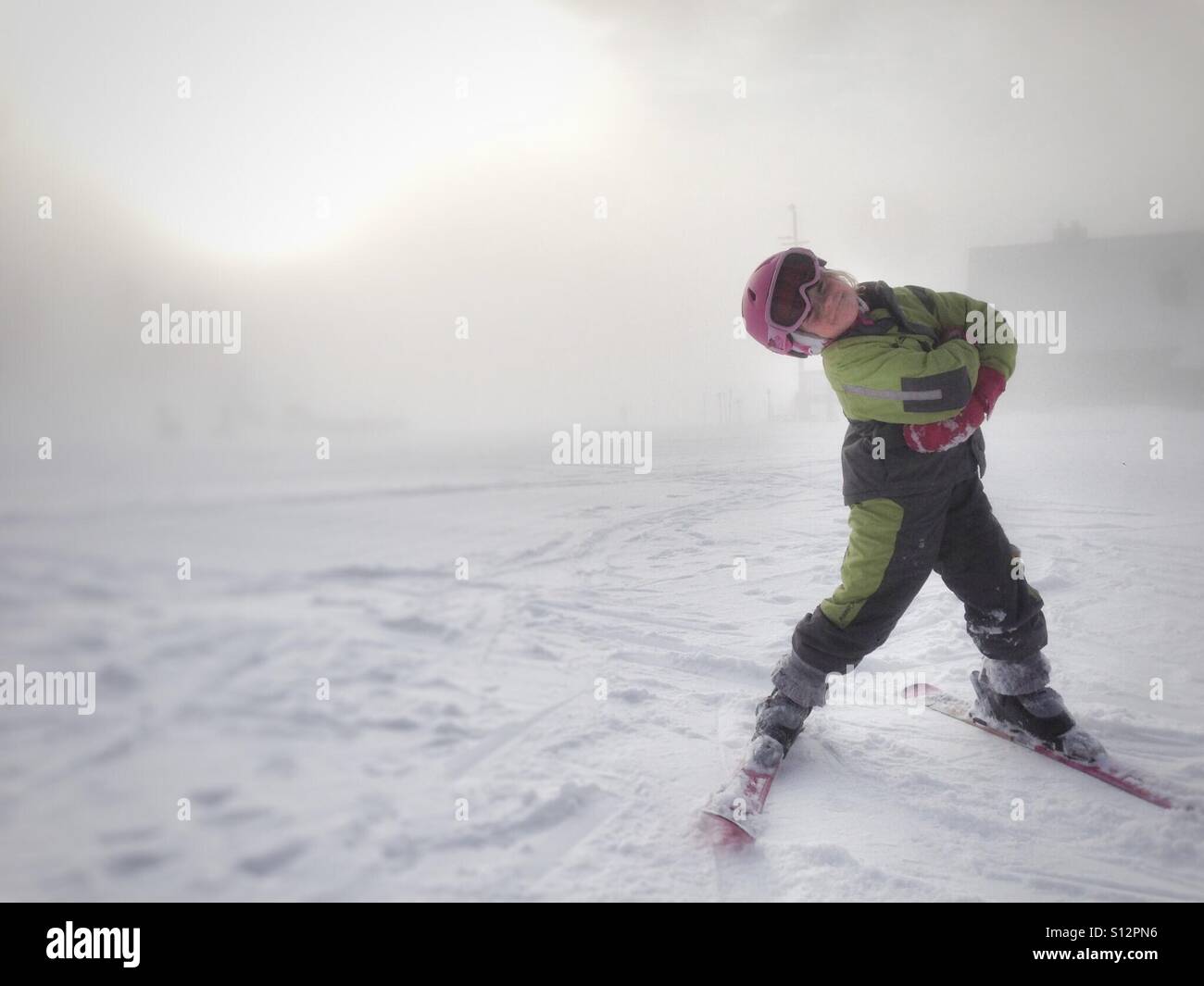 Eine Mädchen zeigt ihre Haltung auf dem Skihügel. Stockfoto