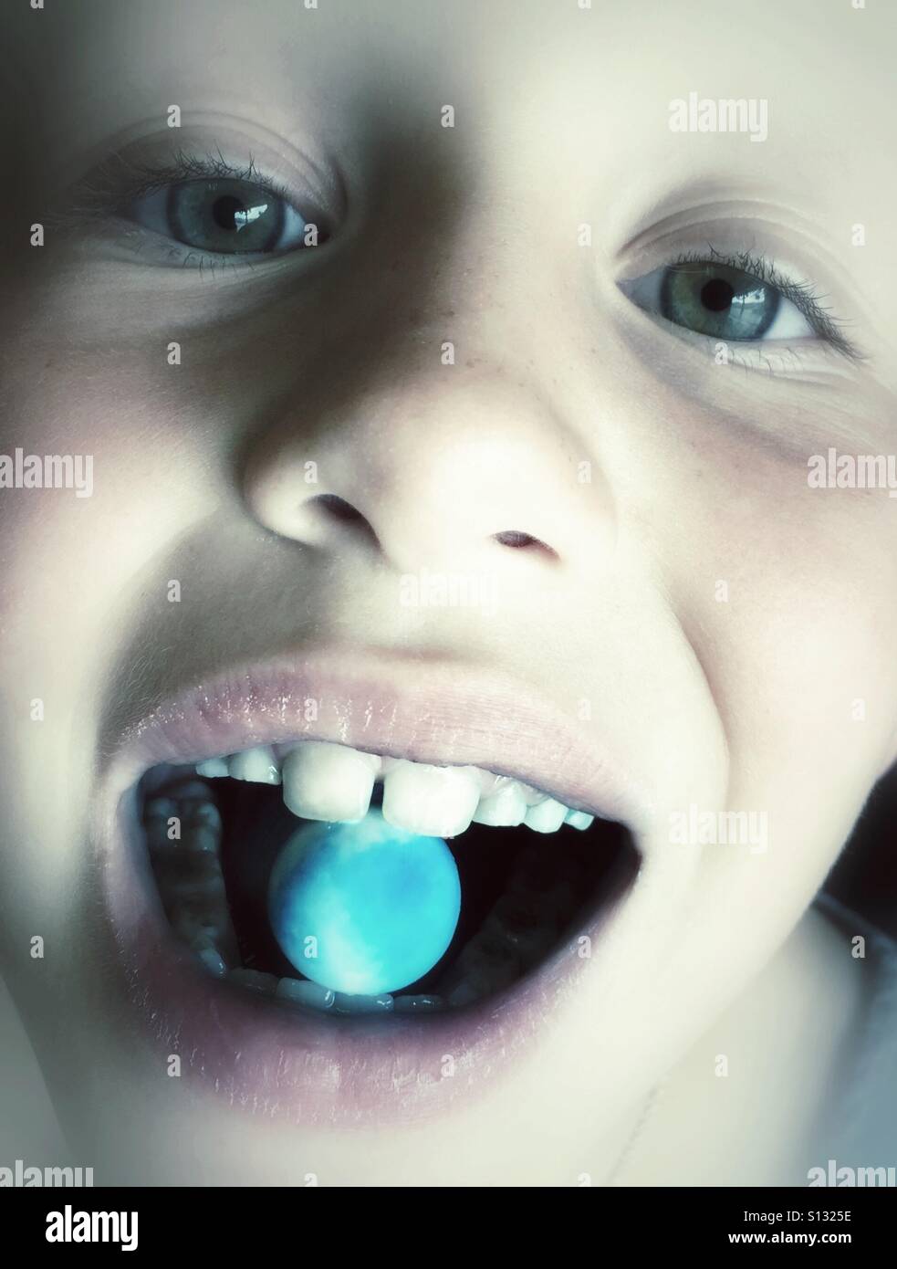 Eine Nahaufnahme eines Kindes mit einer blauen Gumball im Maul. Stockfoto