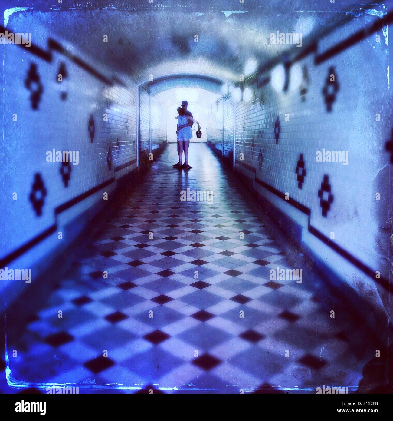 Tunnel der Liebe... ein paar umarmt in einen Fußgängertunnel mit Art-Deco-Fliesen - Smartphone-aufgenommenes Stockfoto