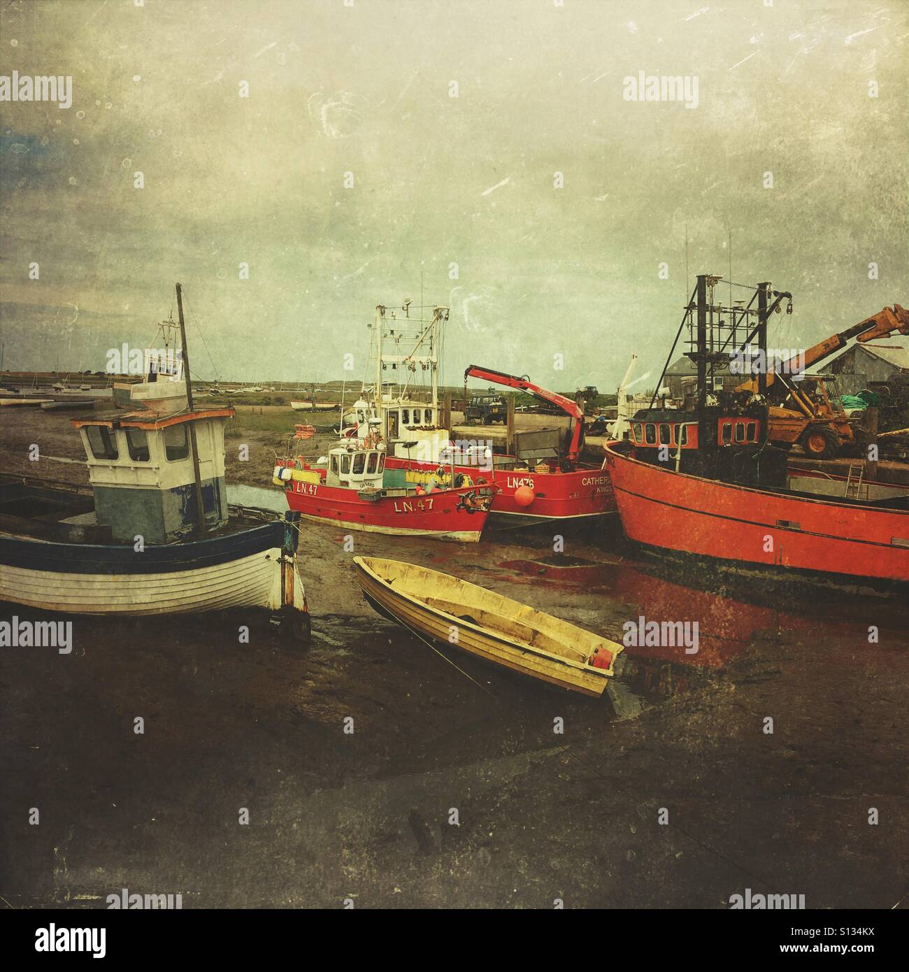 Fischerboote liegen bei Ebbe in einem funktionierenden Küstenhafen, was die Realitäten der traditionellen Fischwirtschaft widerspiegelt. - Smartphone-aufgenommenes Stockfoto