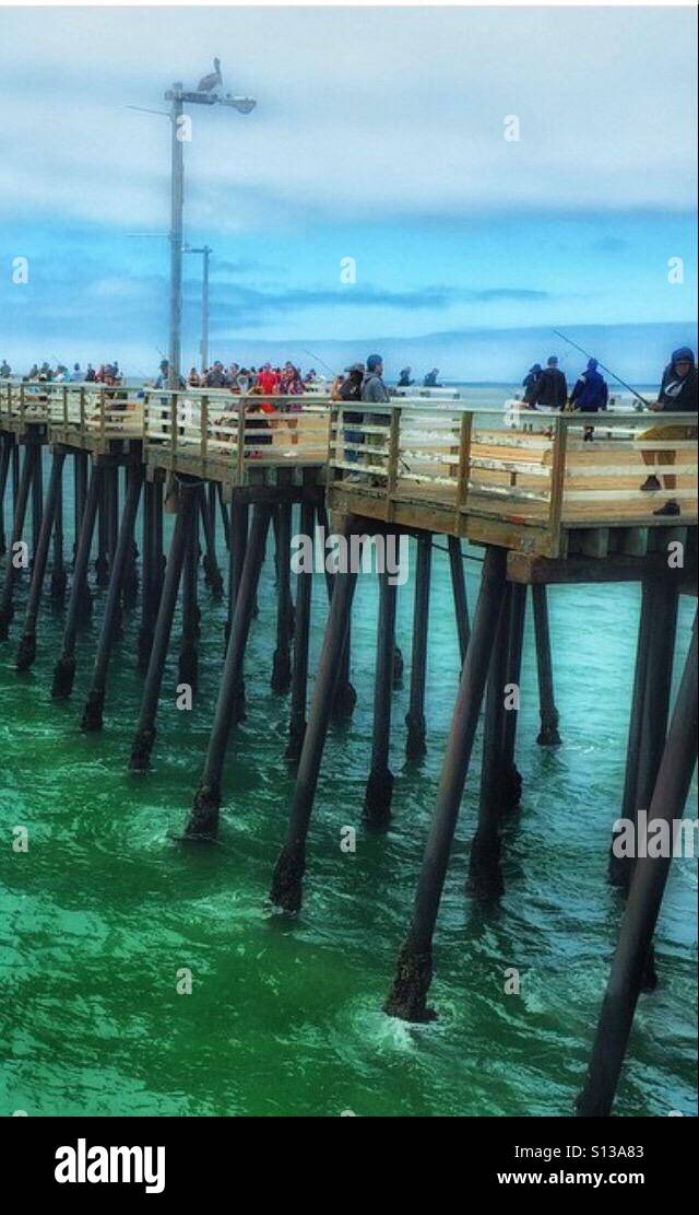 Menschen auf dem Pier Fischfang, zu Fuß... Pelikan auf Top Lichtmast Stockfoto