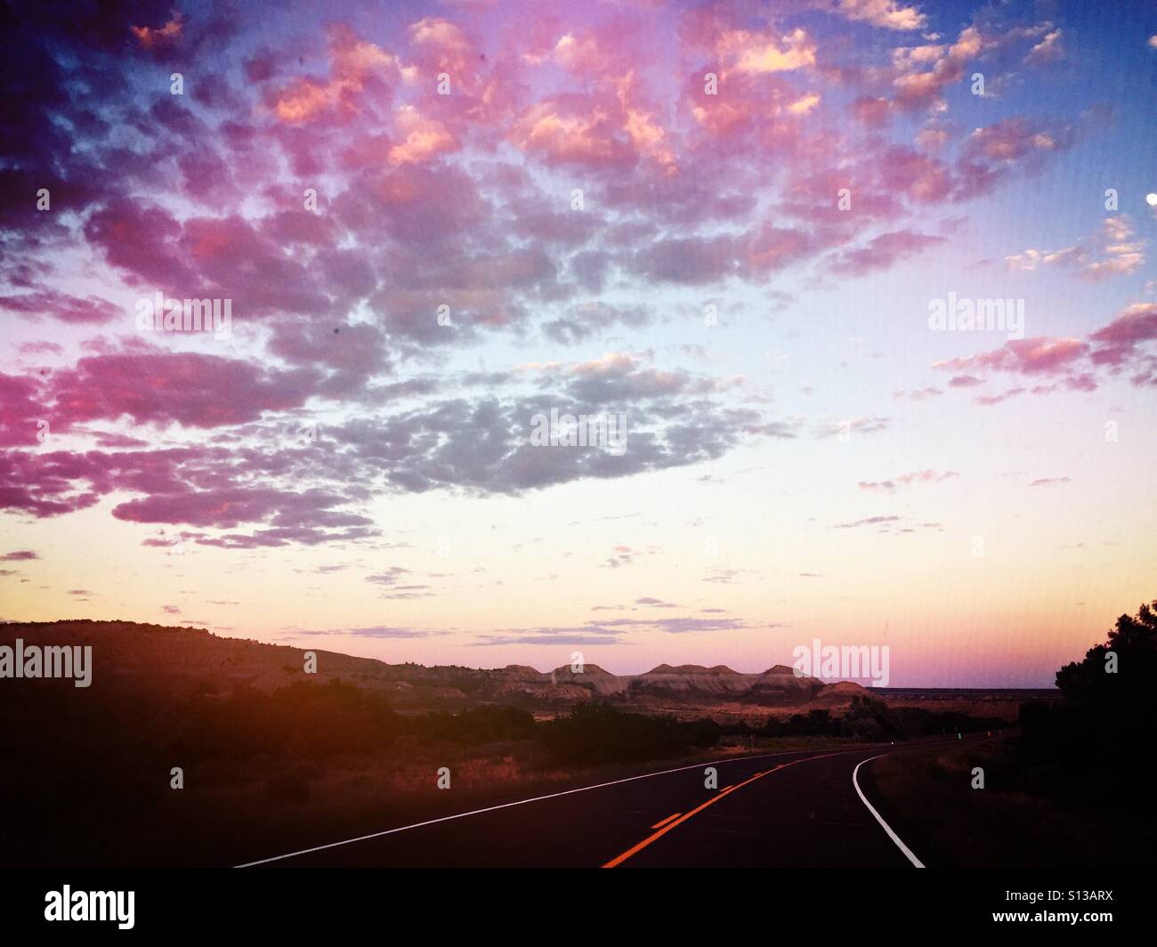 Einem farbenfrohen Sonnenuntergang Himmel über eine Autobahn, die in die Ferne führt. Stockfoto