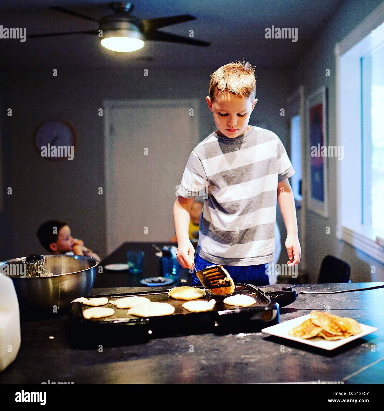 Junge, die Pfannkuchen in der Küche zubereiten Stockfoto