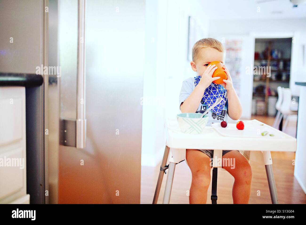 Kleinkind beim Mittagessen zu Hause in einem Hochstuhl Stockfoto