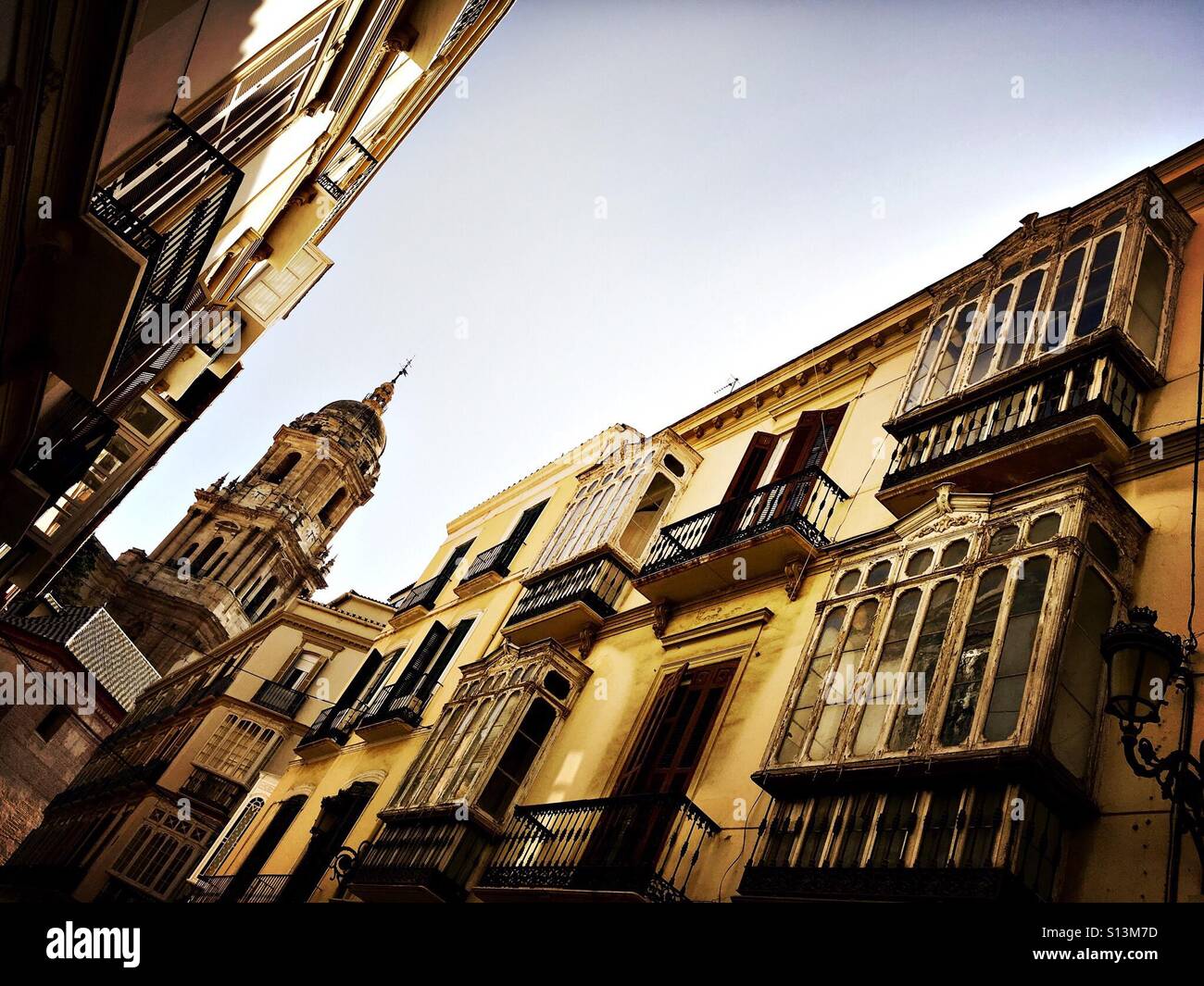 Ansicht der Kathedrale von Málaga durch enge Gassen mit reich verzierten Balkonen Stockfoto