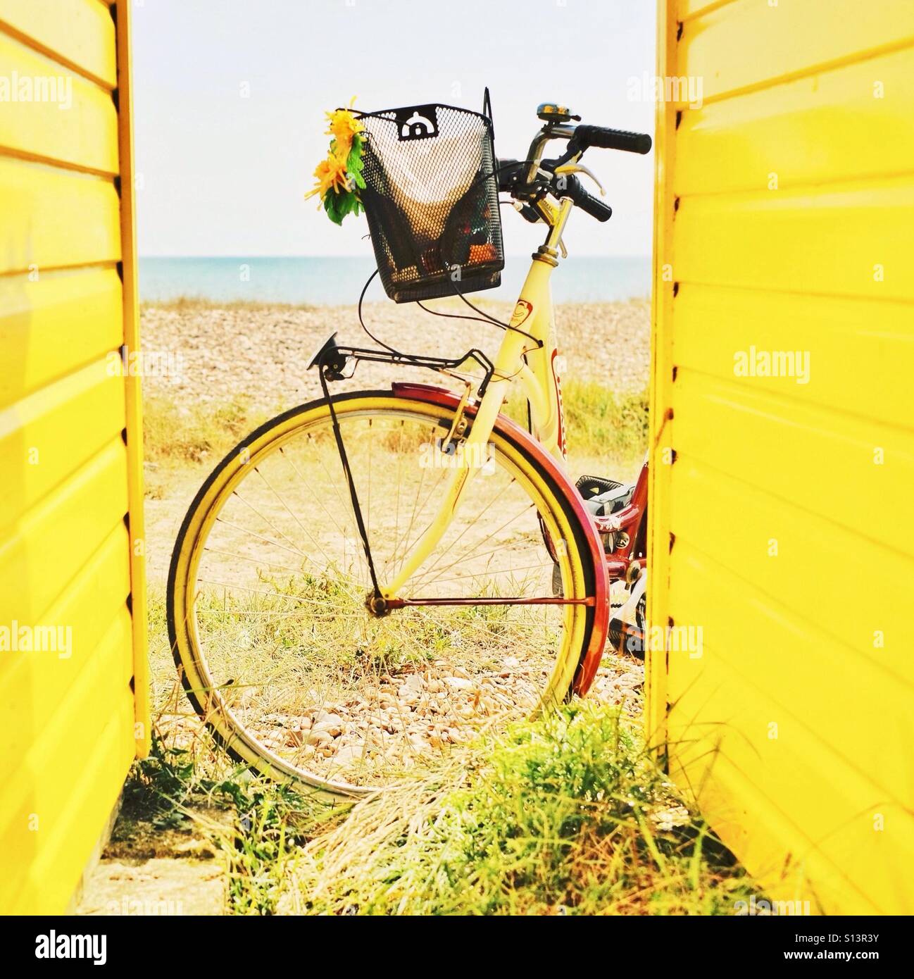 Ein gelbes Fahrrad und Strandhütten im Sommer am Meer Stockfoto