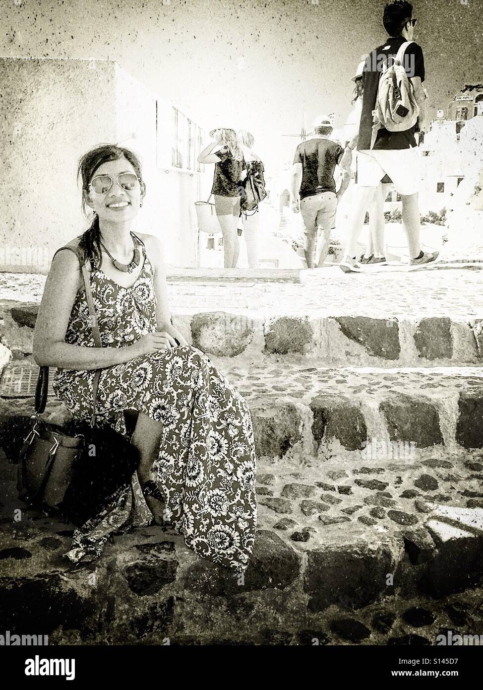 Eine Dame sitzt auf einige Schritte in die Stadt Oia auf der griechischen Insel Santorin. - Smartphone-aufgenommenes Stockfoto