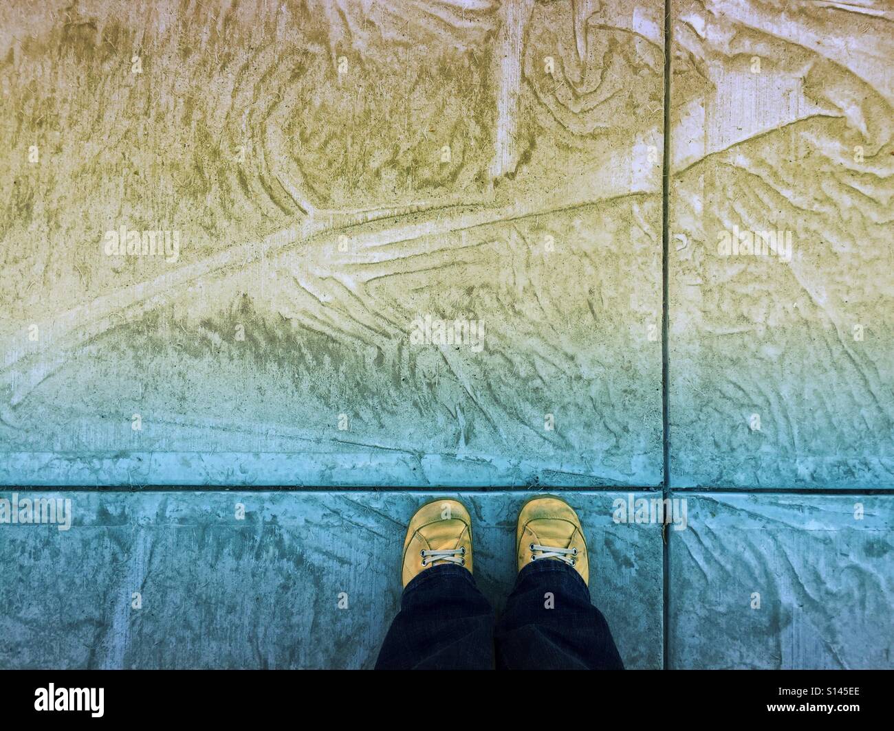 Neuer Beton gekennzeichnet durch eine Plastikfolie während noch nass wird eine raue künstlerische Leinwand für schmutzig gelbe Schuhe. Stockfoto