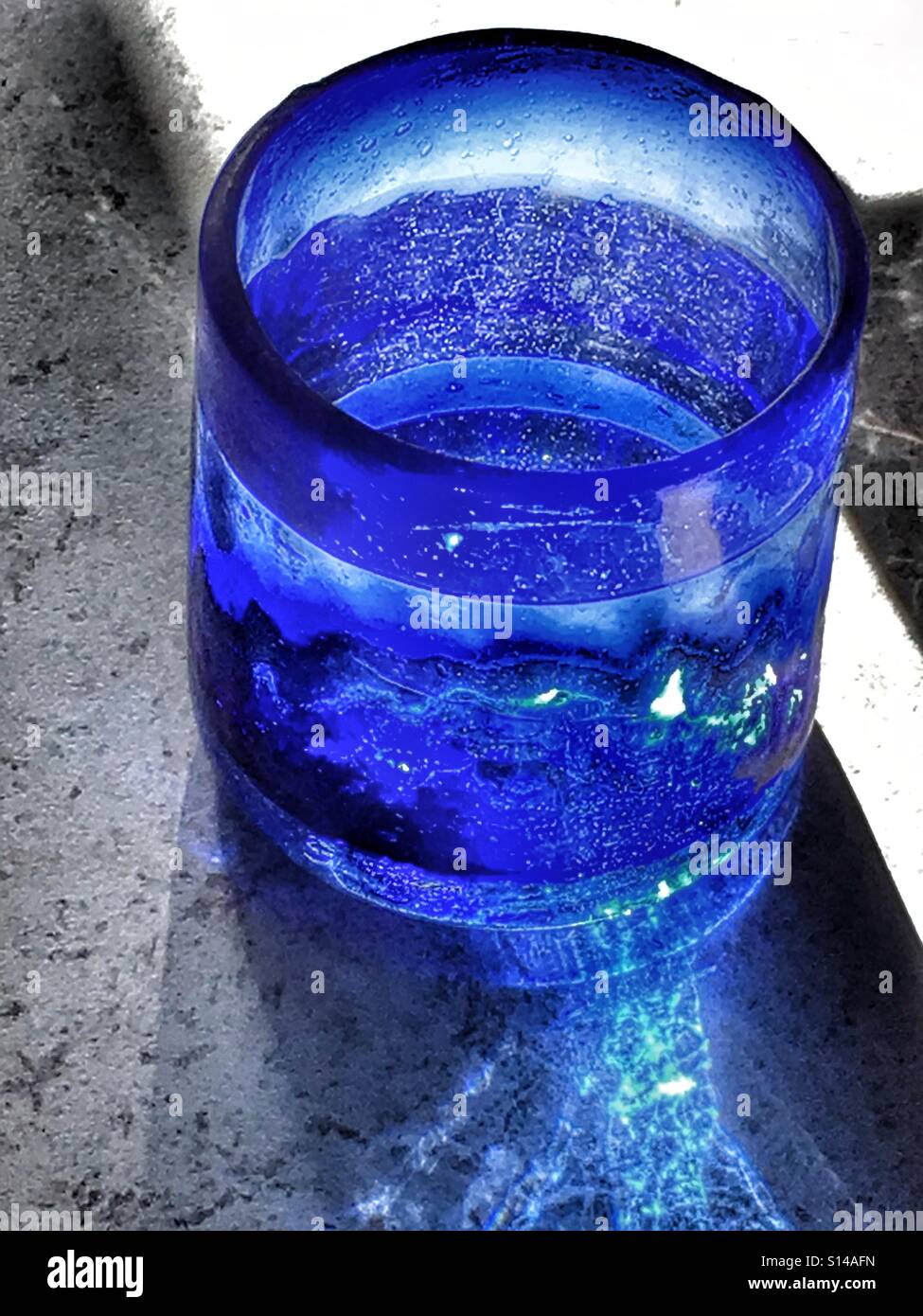 Glas Wasser in blau, mundgeblasenes Glas. Gegenlicht Stockfoto