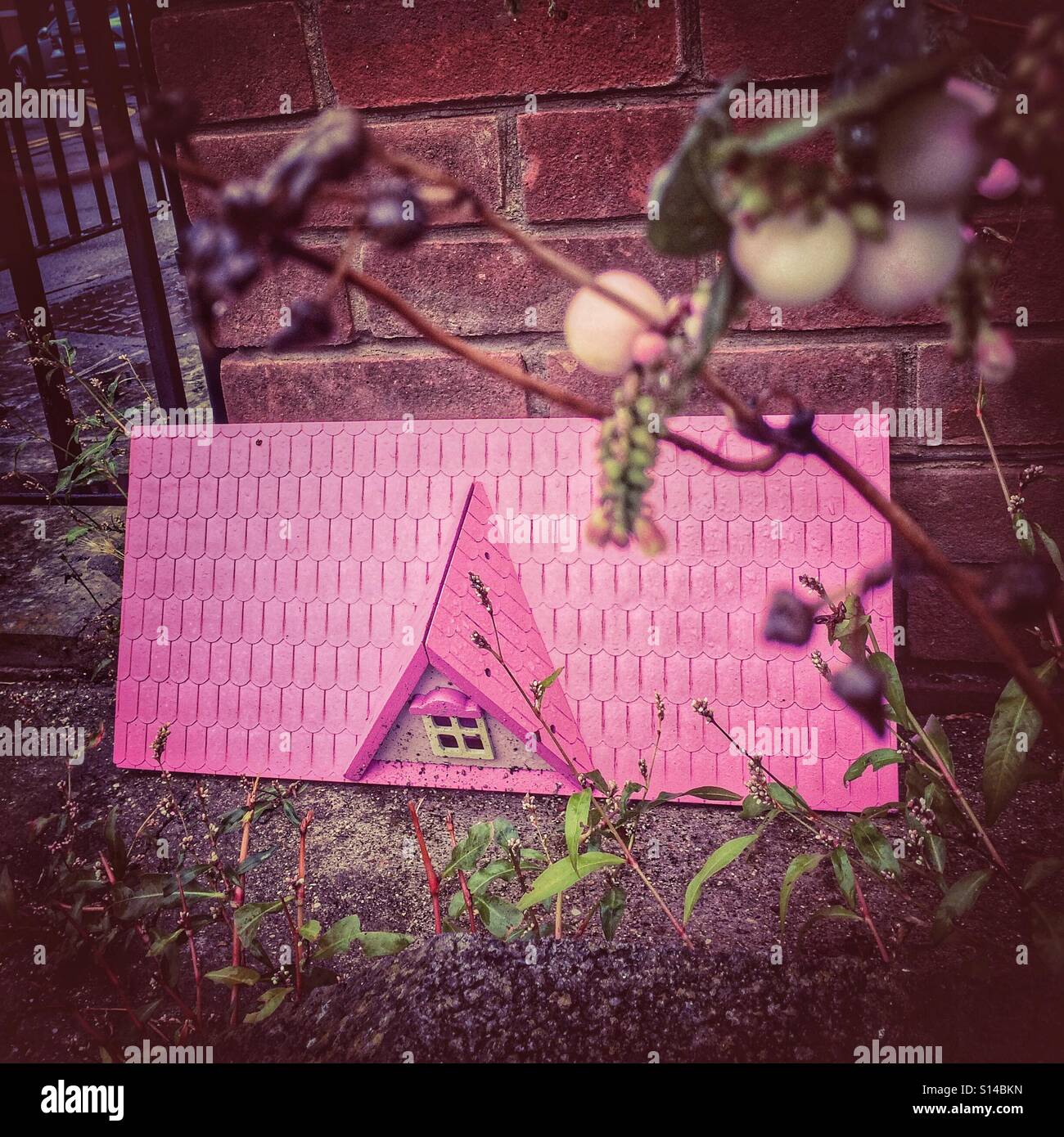 Rosa Puppenhaus Dach durch eine Wand geworfen - Smartphone-aufgenommenes Stockfoto