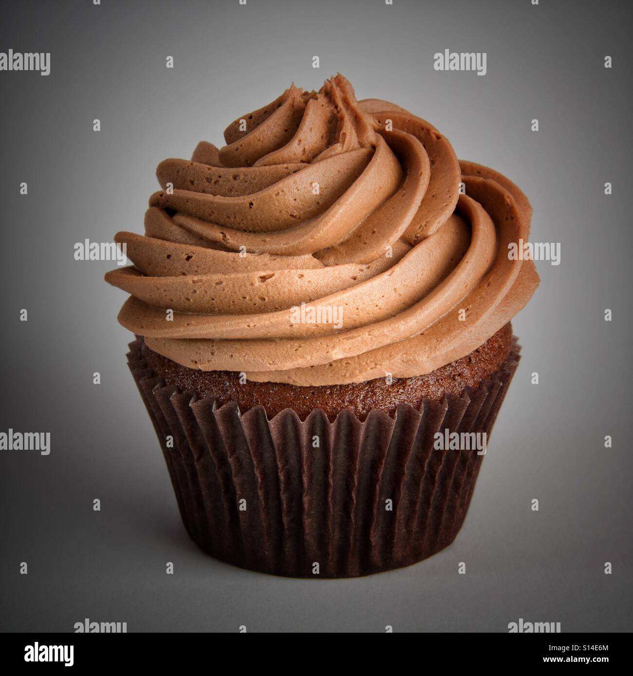 Eine große Schokolade Cupcake mit wirbelte Zuckerguss auf einem isolierten weißen Hintergrund. Stockfoto