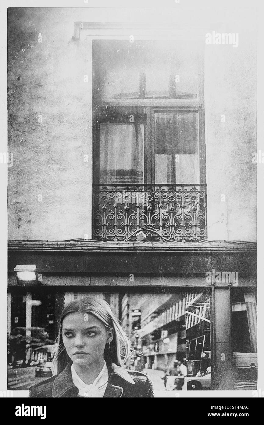 Schöne Frau unter einem Fenster mit Blick seitlich - Smartphone-aufgenommenes Stockfoto