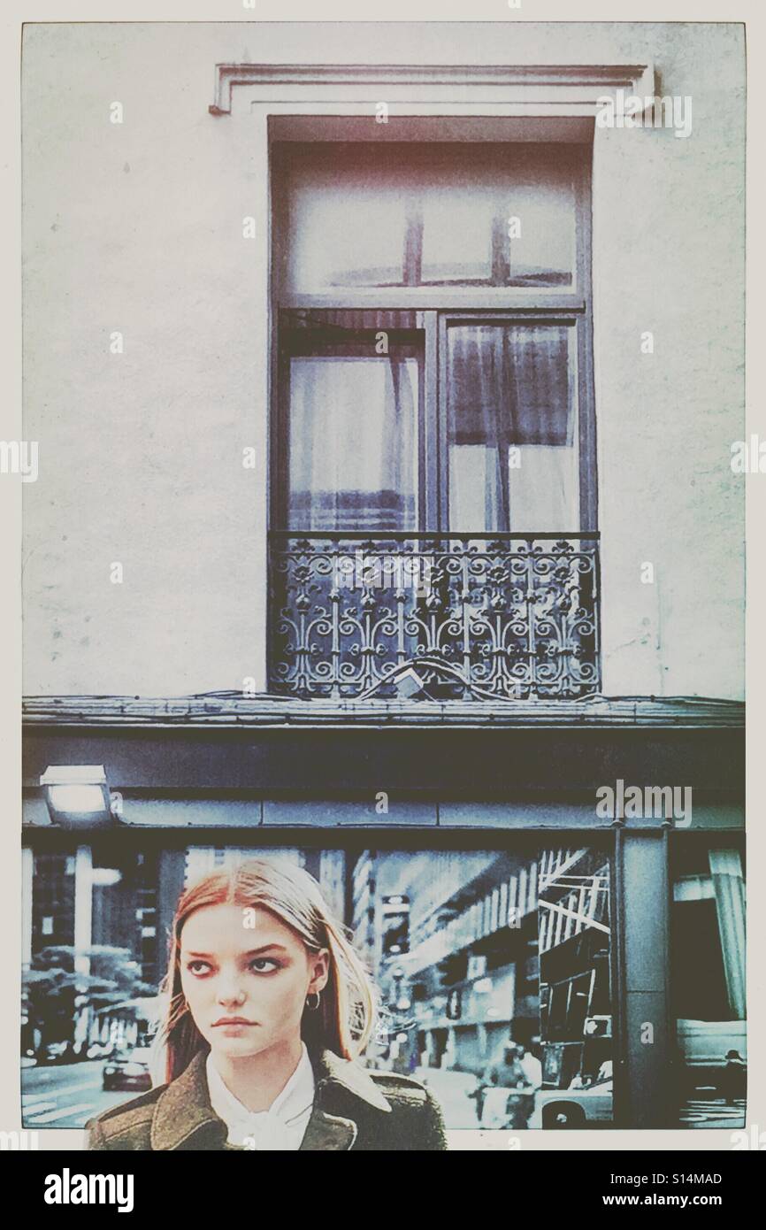 Schöne Frau unter einem Fenster mit Blick seitlich - Smartphone-aufgenommenes Stockfoto