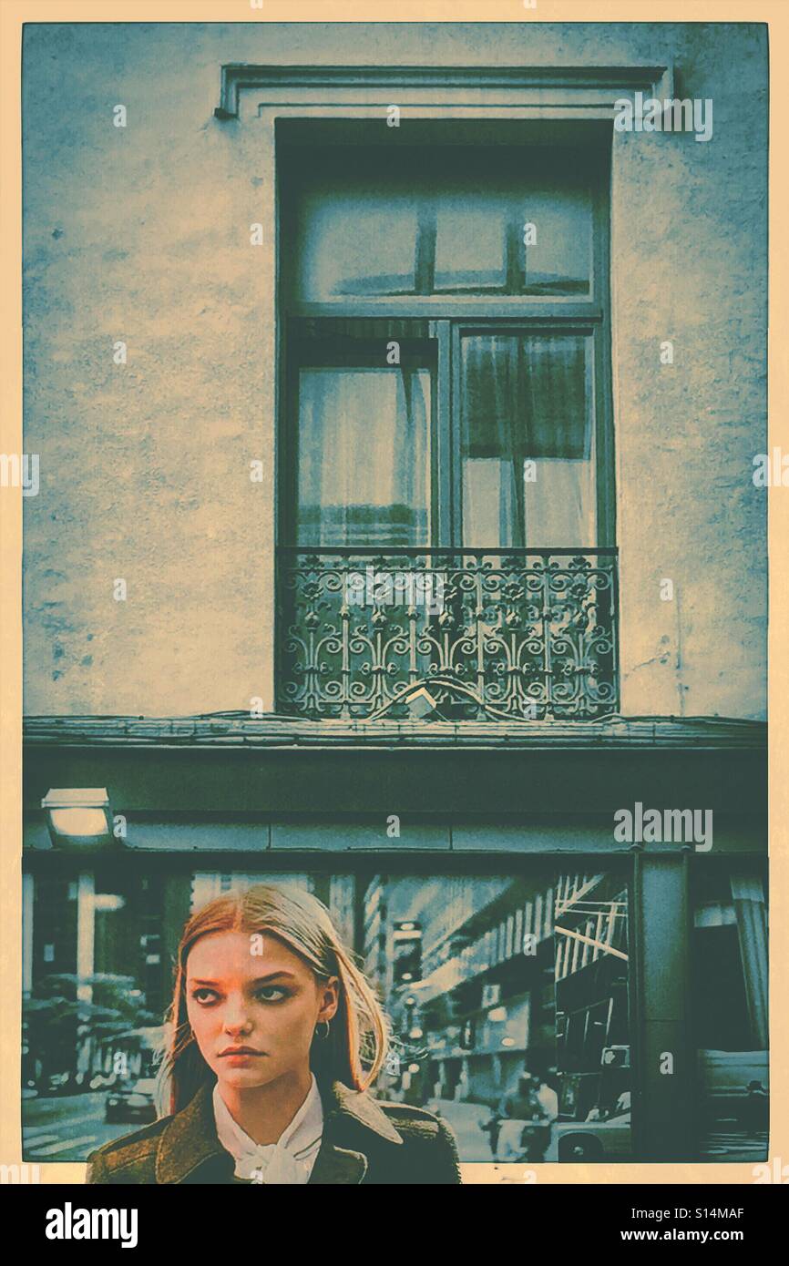 Schöne Frau unter einem Fenster mit Blick seitlich - Smartphone-aufgenommenes Stockfoto