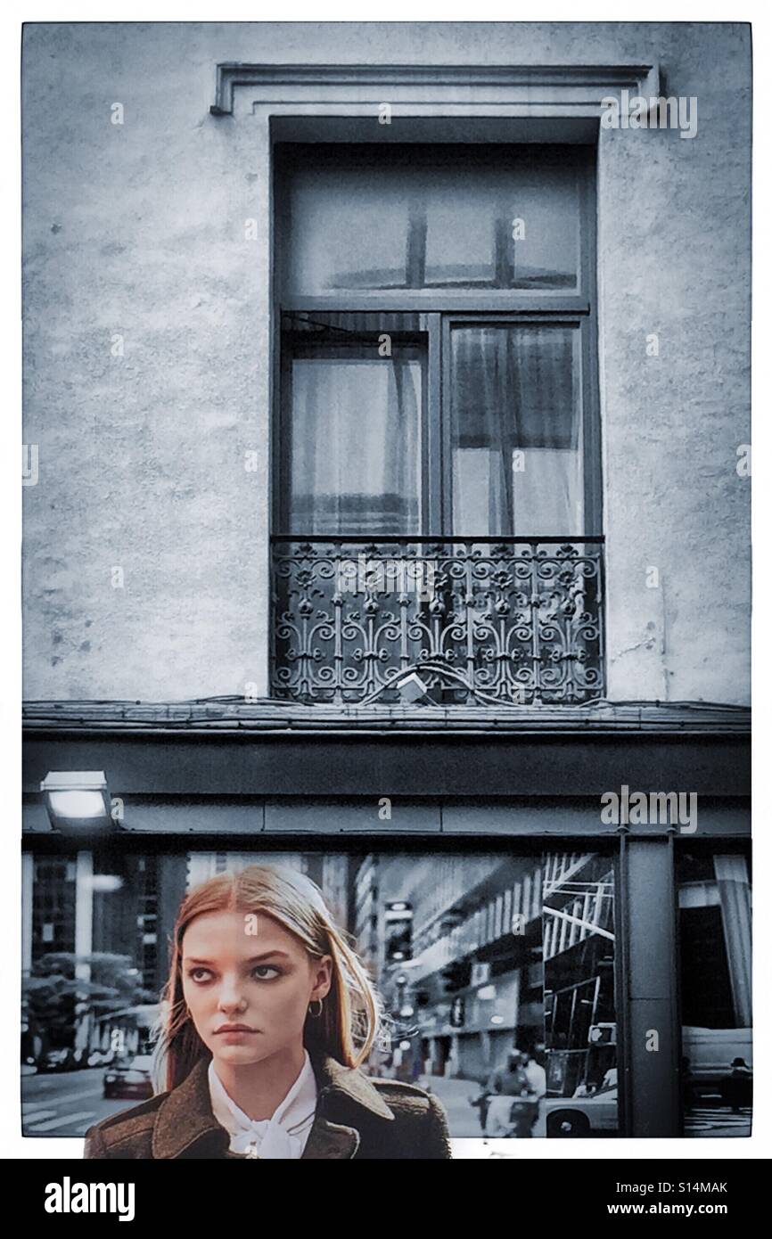 Schöne Frau unter einem Fenster mit Blick seitlich - Smartphone-aufgenommenes Stockfoto