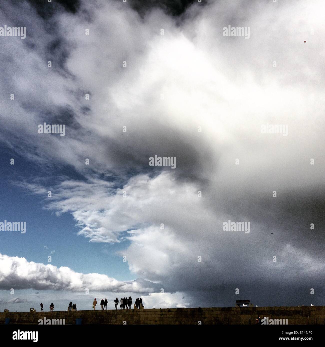 Die Menschen gehen entlang der Wand Sturm im Hafen von Howth Grafschaft Dublin, auf einen stürmischen Herbst Sonntagnachmittag in Irland. Stockfoto