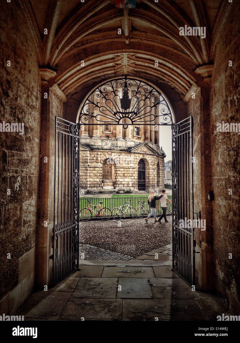 Paar Vorbeigehen die Radcliffe Camera, gesehen durch einen Durchgang von der Bodleian Library, University of Oxford, England - Smartphone-aufgenommenes Stockfoto