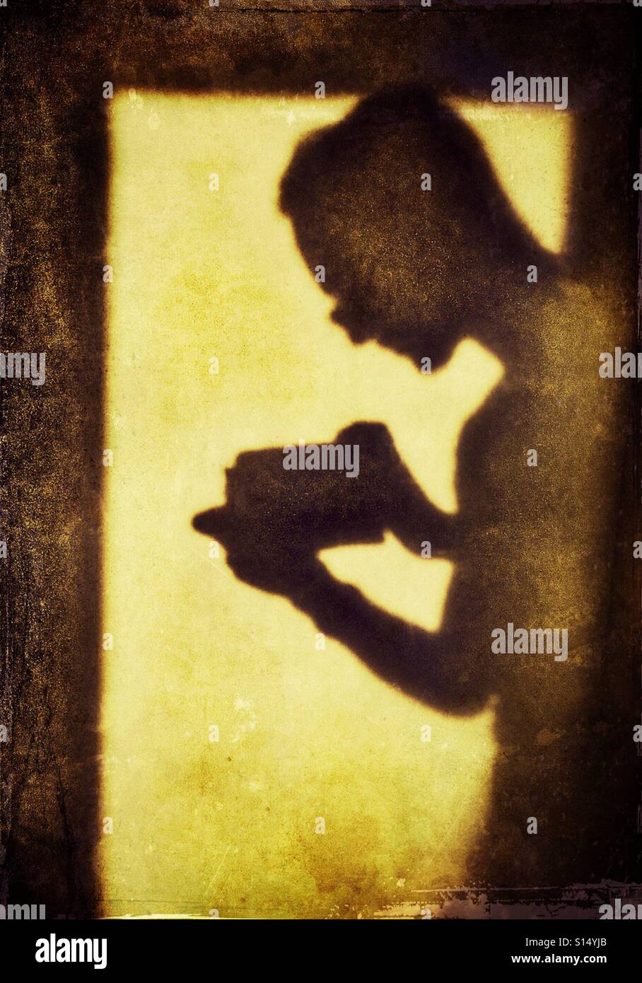 Schatten der Figur mit einem Kamera-Handy durch ein Fenster Stockfoto