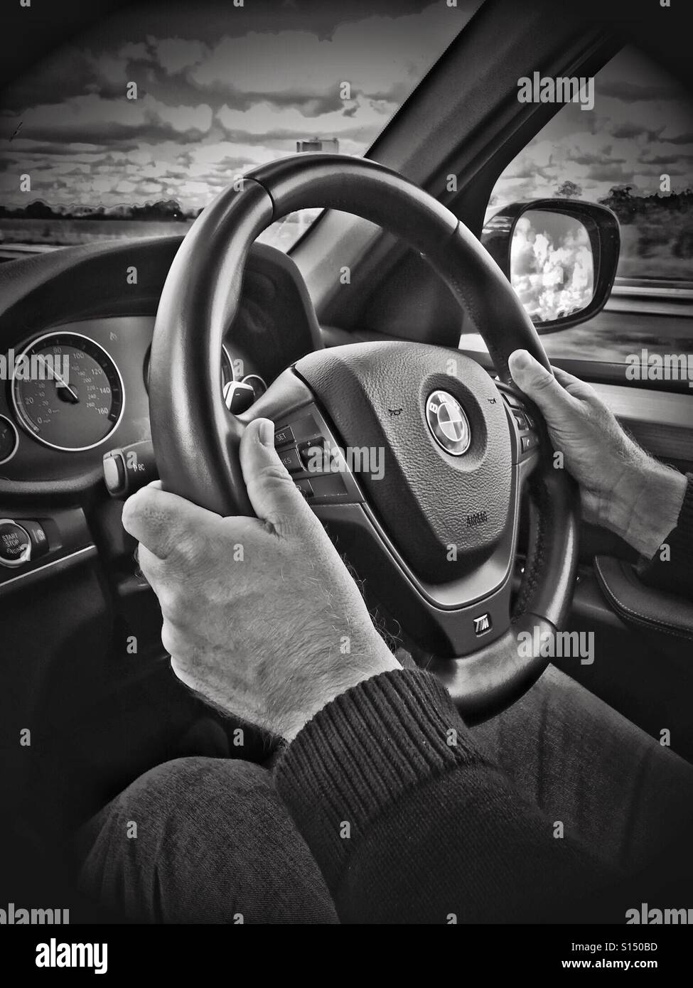 Auf dem Fahrersitz. Mann fahren BMW zeigt Hände und Lenkrad. - Smartphone-aufgenommenes Stockfoto