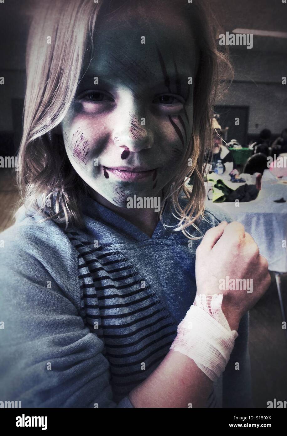 Ein Mädchen mit einem bandagierten Handgelenk und Zombie-Gesicht zu malen. - Smartphone-aufgenommenes Stockfoto