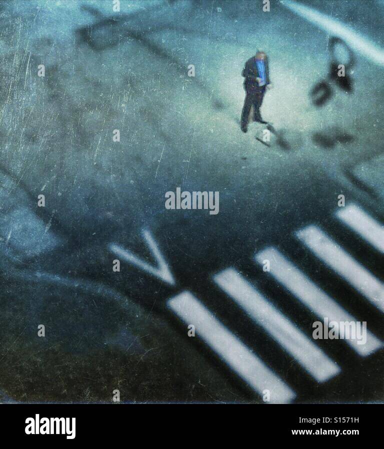 Einsamer Geschäftsmann stehend auf einer Kreuzung Blick auf seinem smartphone - Smartphone-aufgenommenes Stockfoto