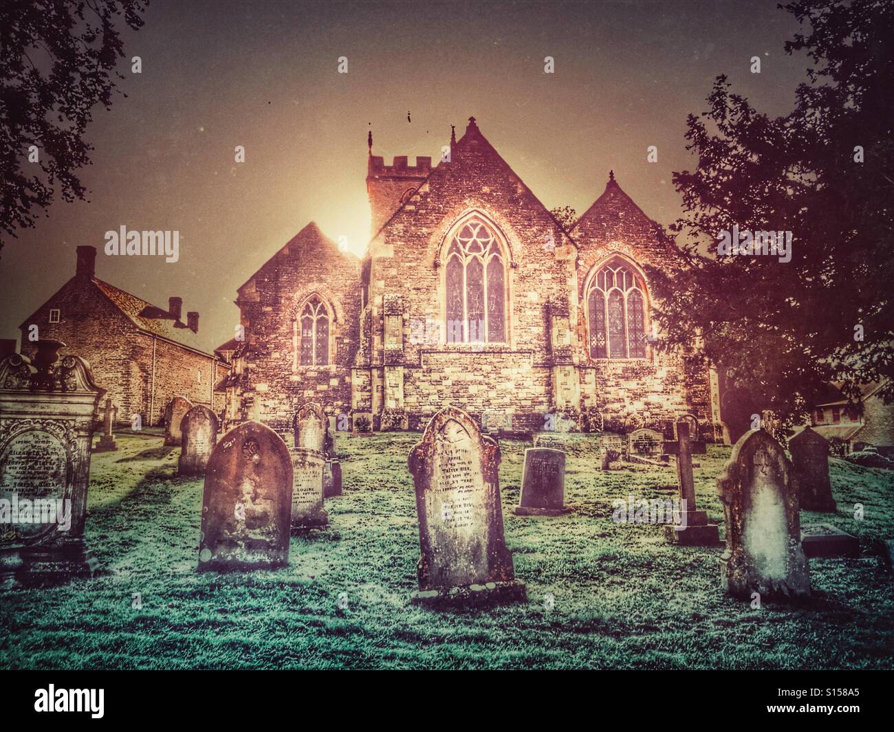 Sonne hinter St.-Nikolaus-Kirche und Friedhof, Henstridge, Somerset, England - Smartphone-aufgenommenes Stockfoto