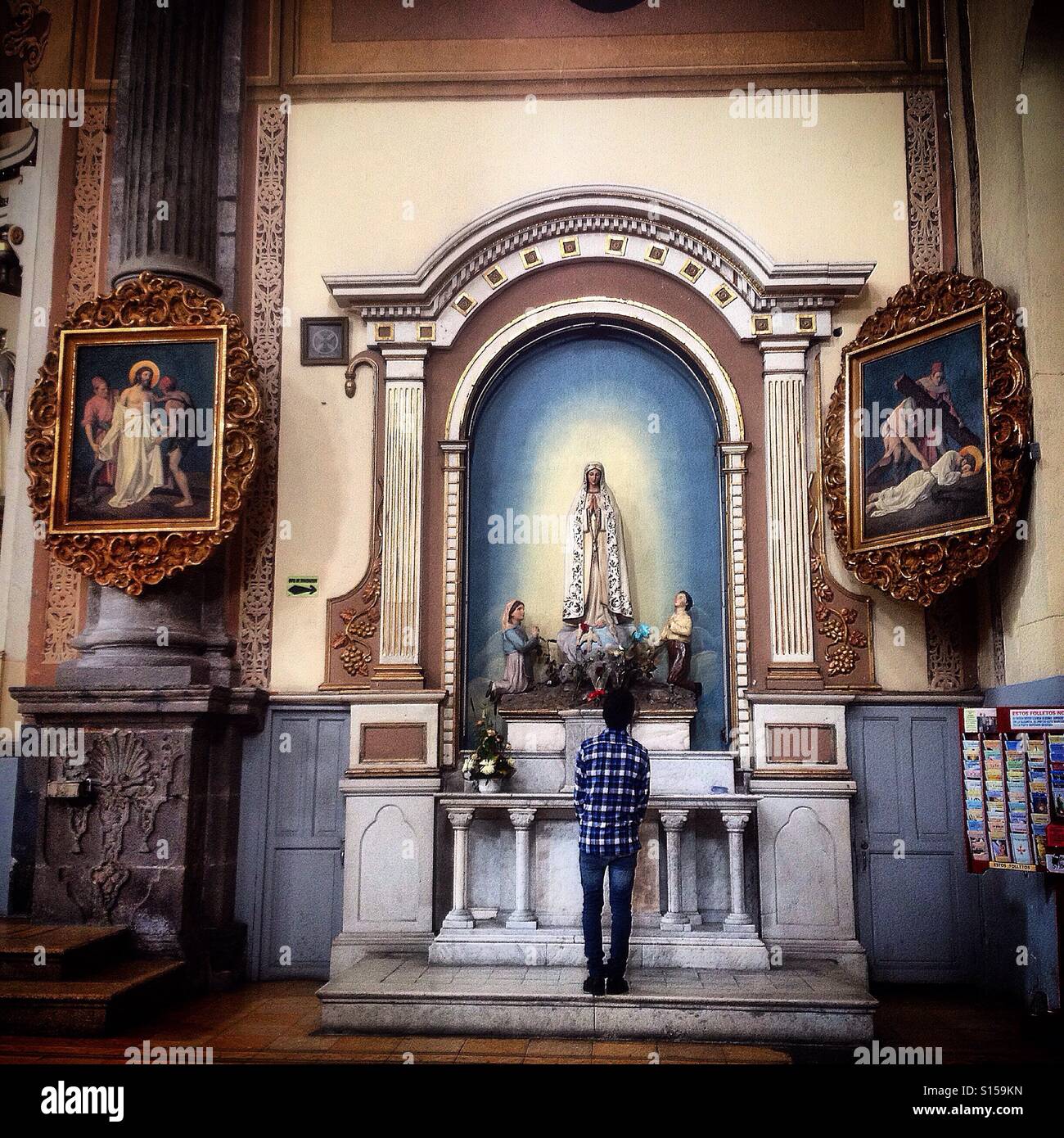 Ein junger Mann betet zu unserer lieben Frau von Fatima in La Compañía Templo del Espiritu Santo, in Puebla de Zaragoza, Mexiko - Smartphone-aufgenommenes Stockfoto