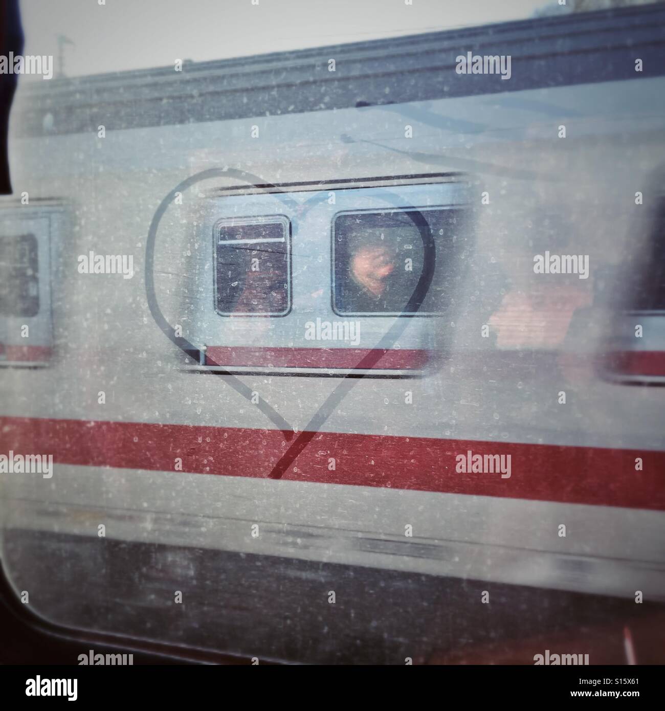 Herzen im Staub auf einem Zugfenster mit der Reflexion des Gesicht einer Frau gezeichnet Stockfoto