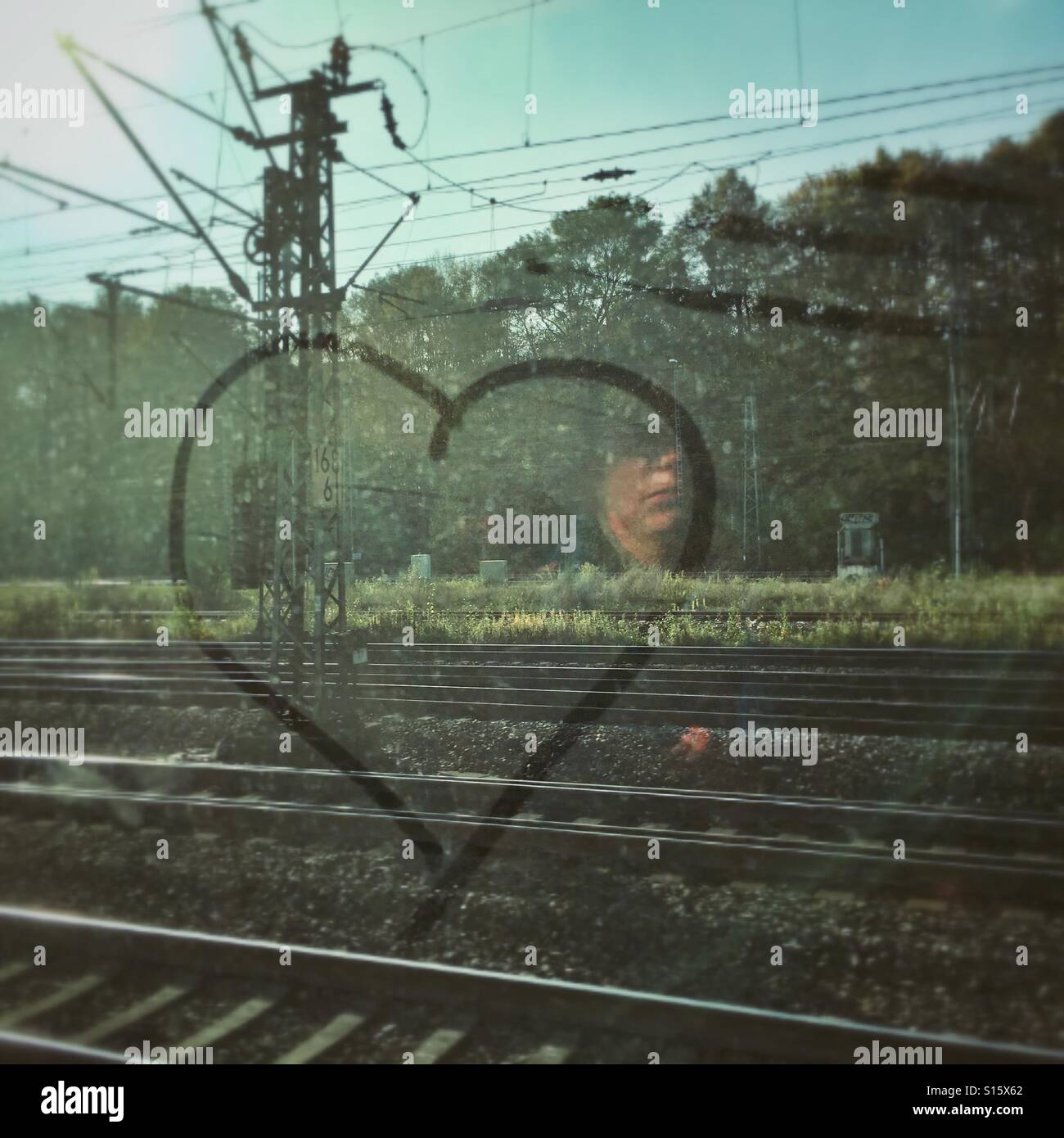 Herzen im Staub auf einem Zugfenster mit der Reflexion des Gesicht einer Frau gezeichnet Stockfoto