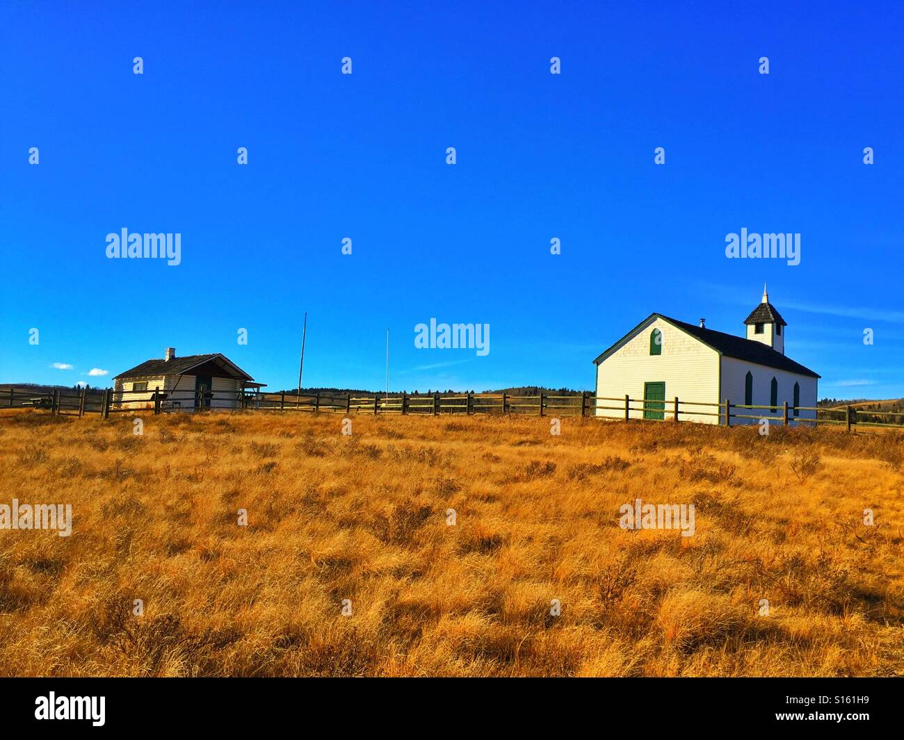 McDougall Memorial United Church.  Sonnenstrahlen, kleine Landkirche und die kanadischen Rockies mit Pfarrhaus Stockfoto