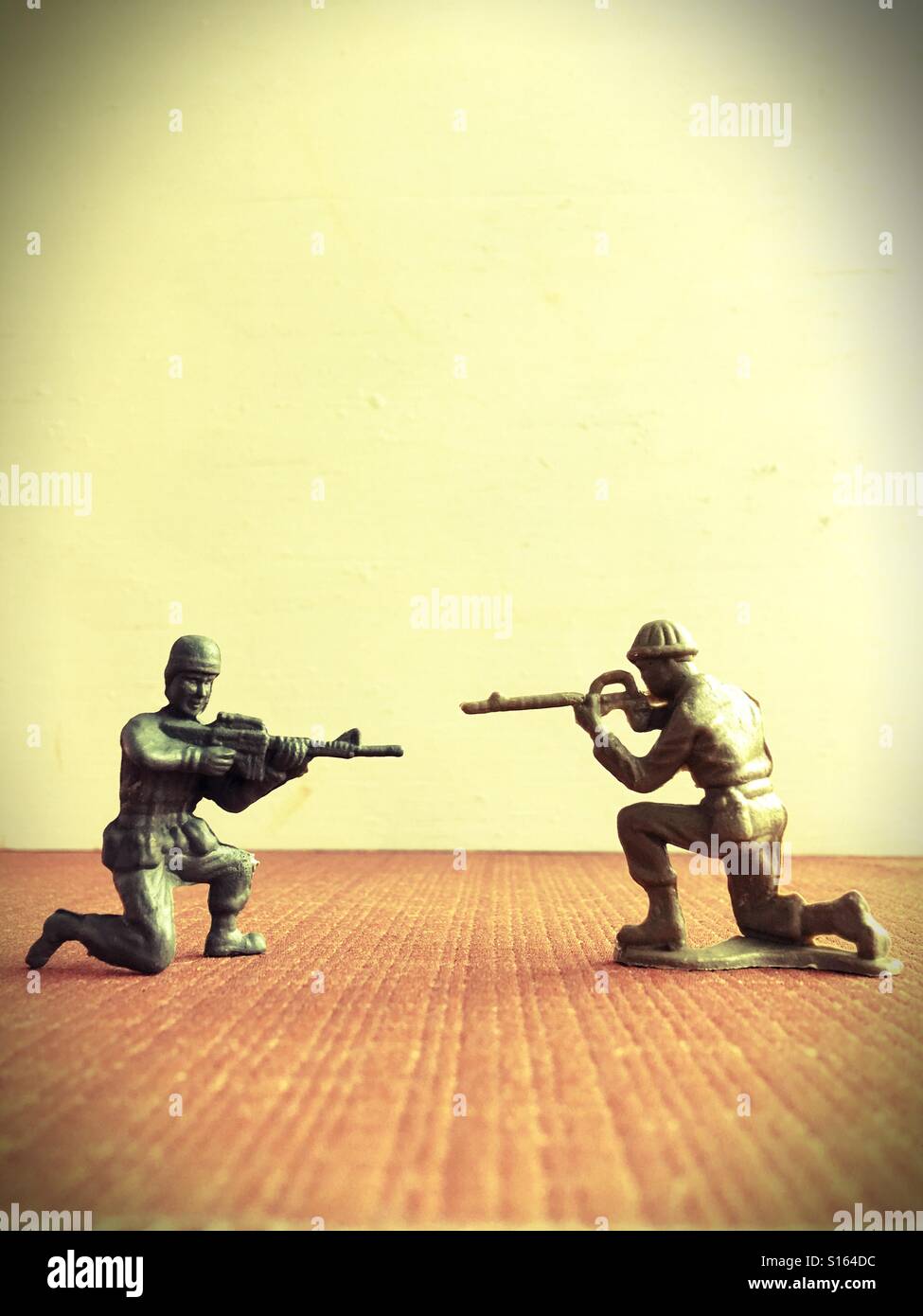 Zwei Spielzeug-Soldaten, die Waffen aufeinander zeigen. Stockfoto