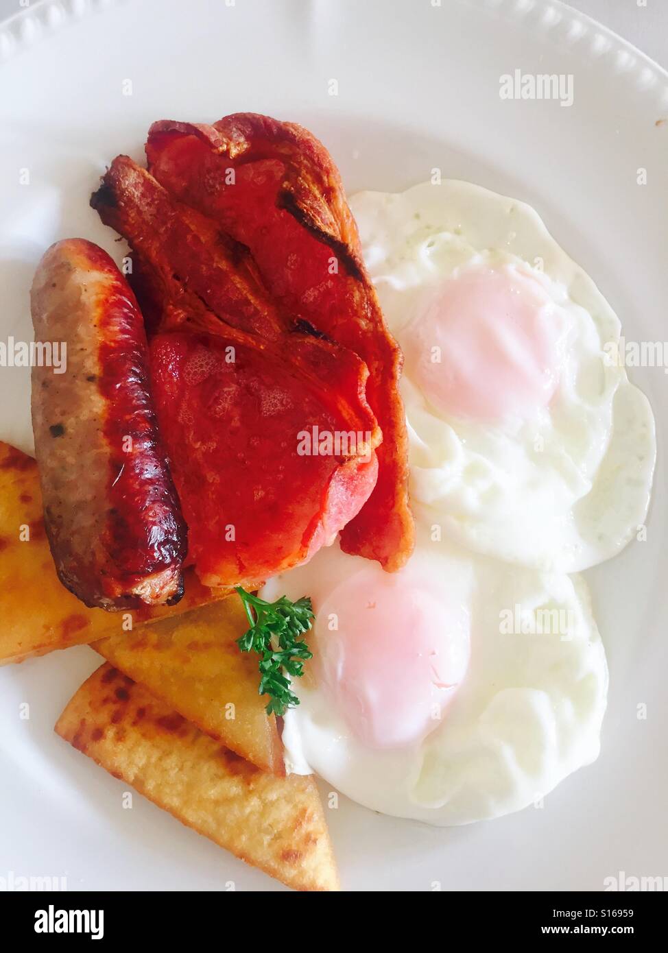 Warmes Frühstück mit Spiegeleiern, Speck, Wurst und Kartoffeln Kuchen Stockfoto