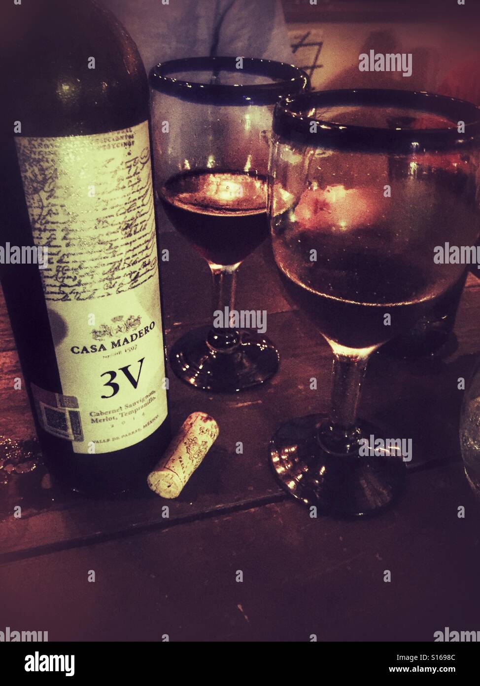 Eine offene Flasche von Casa Madero 3V Wein und zwei Gläser Wein sind auf eine intime Tisch in einem gemütlichen Restaurant in San Pancho, Nayarit angezeigt. Stockfoto