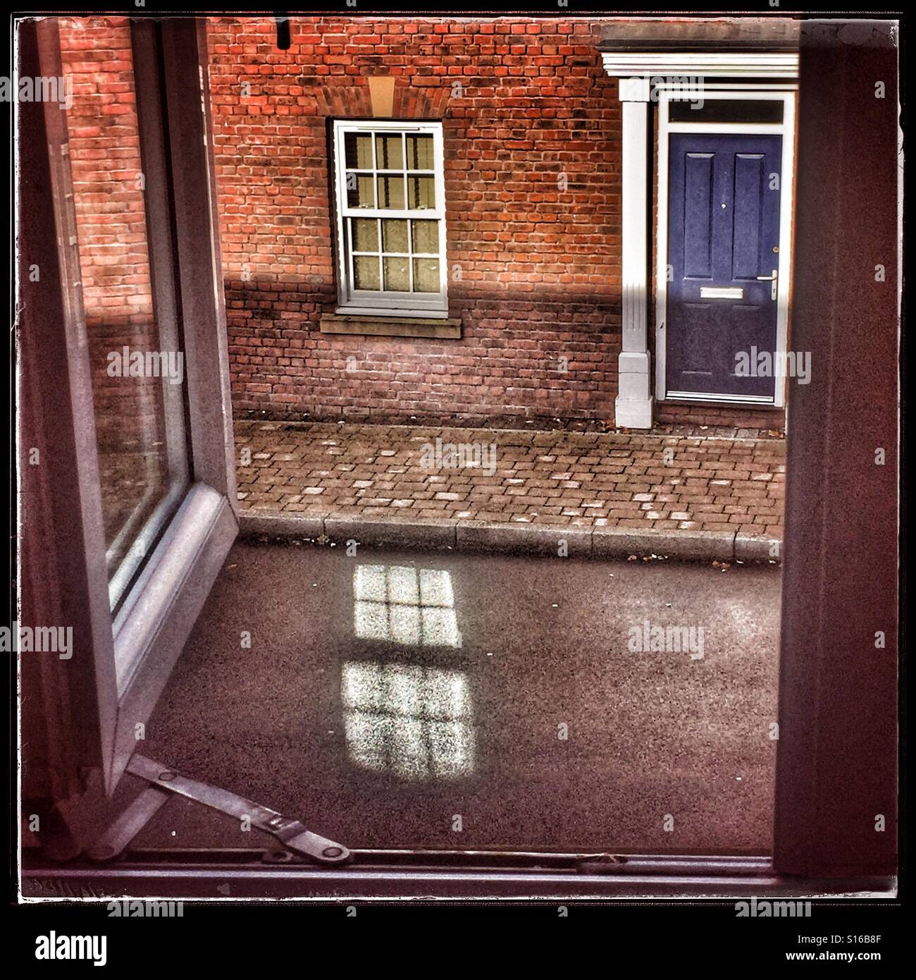 Blick aus dem Fenster auf nasser Straße unten mit Fenster reflektiert es Stockfoto